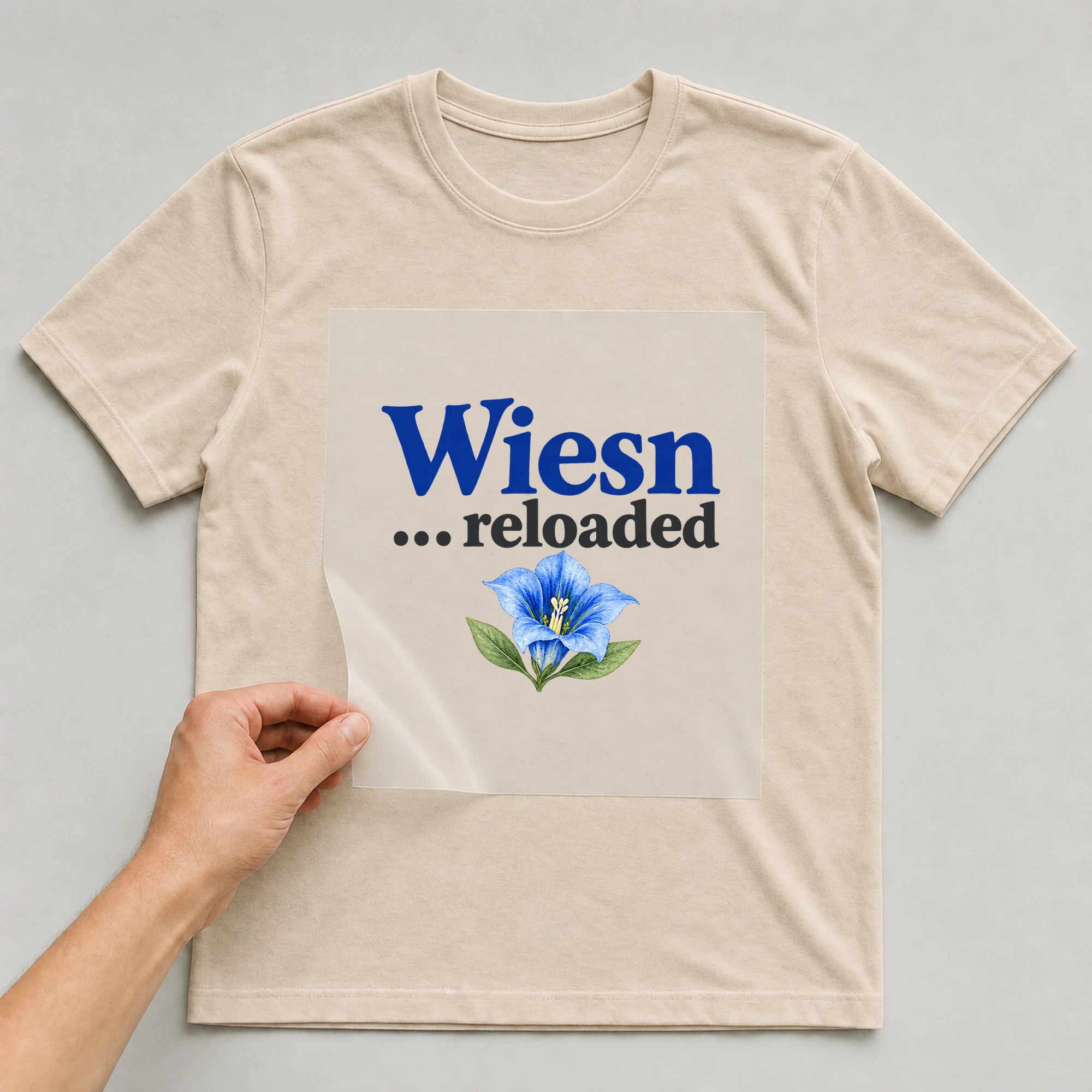 Bügelbild „Wiesn ... reloaded“ auf beigem T-Shirt, Folie wird aufgelegt
