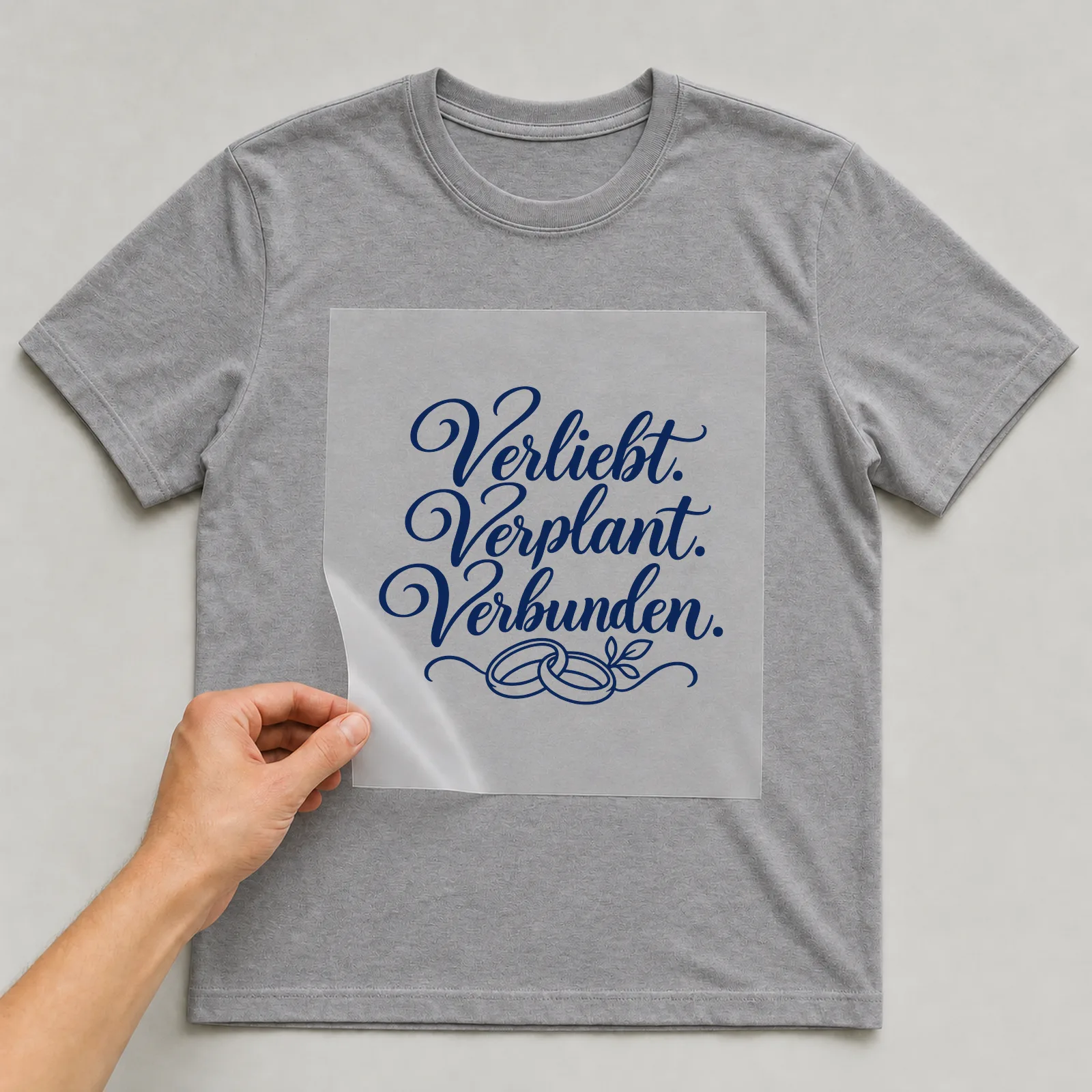 Bügelbild „Verliebt. Verplant. Verbunden.“ auf grauem T-Shirt, Folie wird aufgelegt