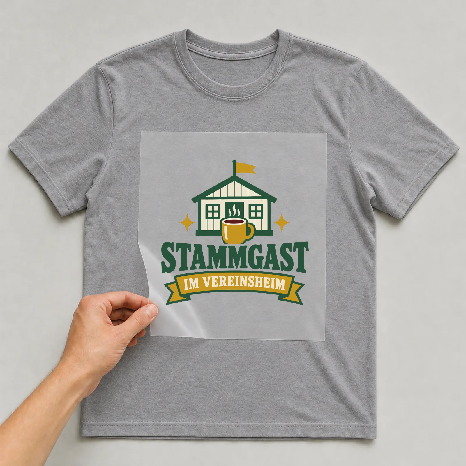 Bügelbild Stammgast im Vereinsheim auf grauem T-Shirt, Folie wird aufgelegt