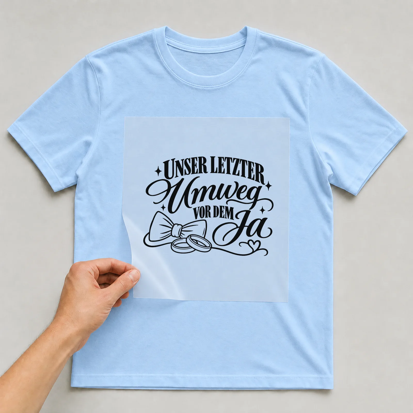Bügelbild „UNSER LETZTER Umweg VOR DEM Ja“ auf hellblauem T-Shirt, Folie wird aufgelegt