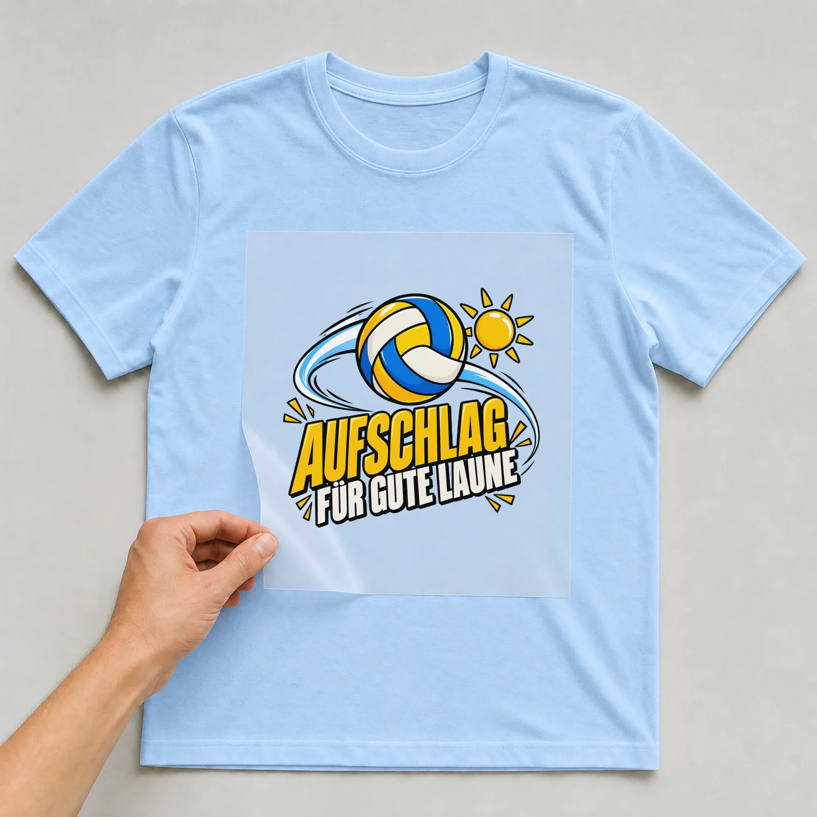 Bügelbild „Aufschlag für gute Laune“ auf hellblauem T-Shirt, Folie wird aufgelegt