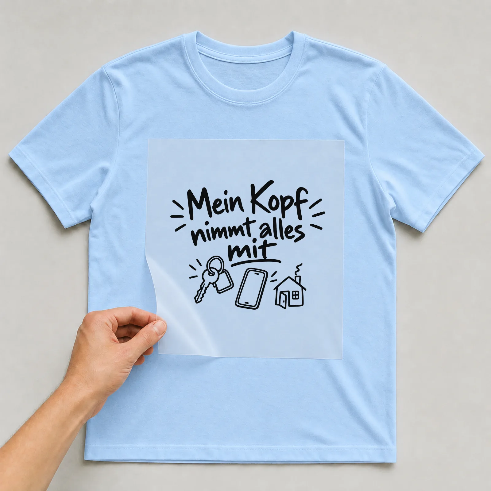 Bügelbild „Mein Kopf nimmt alles mit“ auf hellblauem T-Shirt, Folie wird aufgelegt