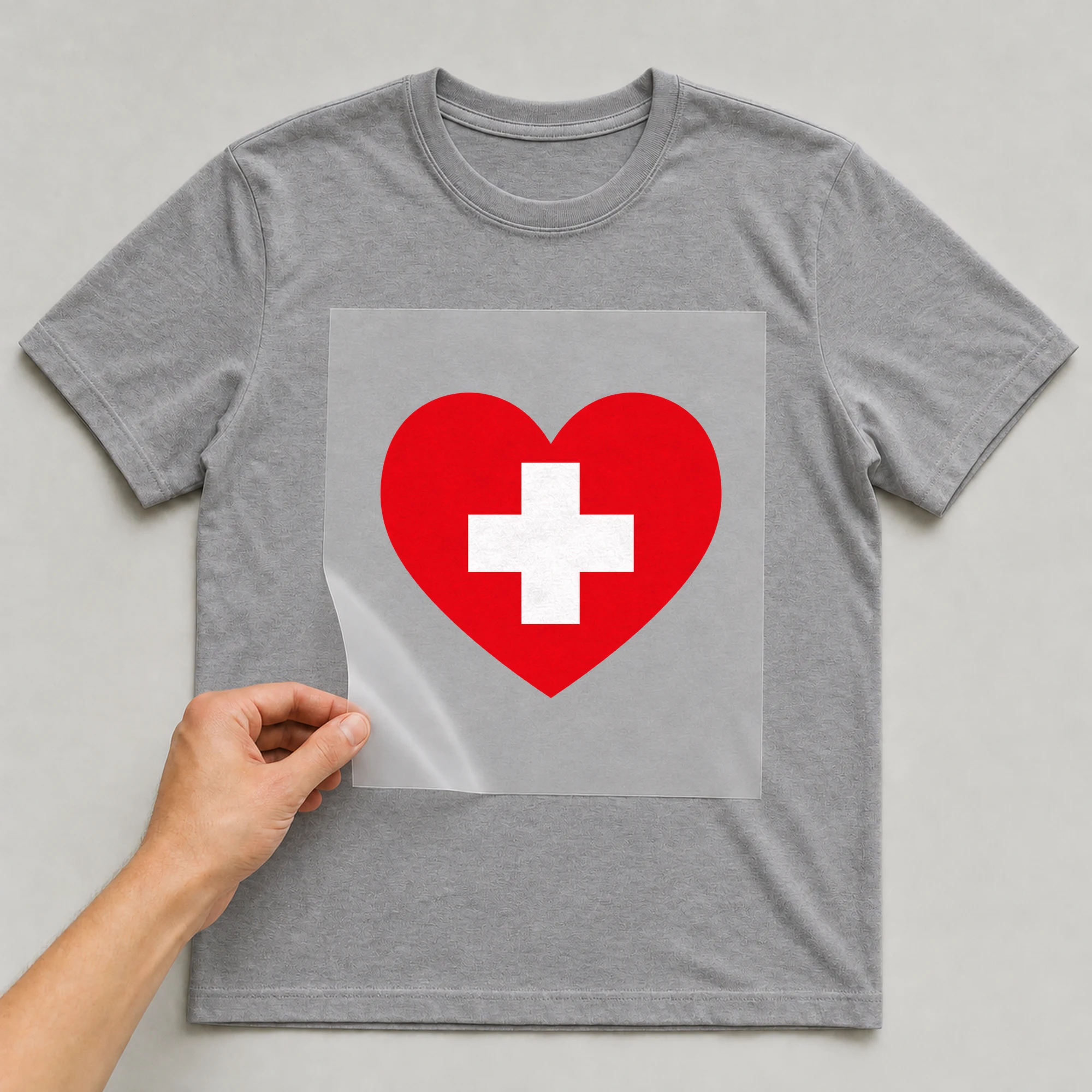 Bügelbild „Herz Flagge Schweiz“ auf grauem T-Shirt, Folie wird aufgelegt