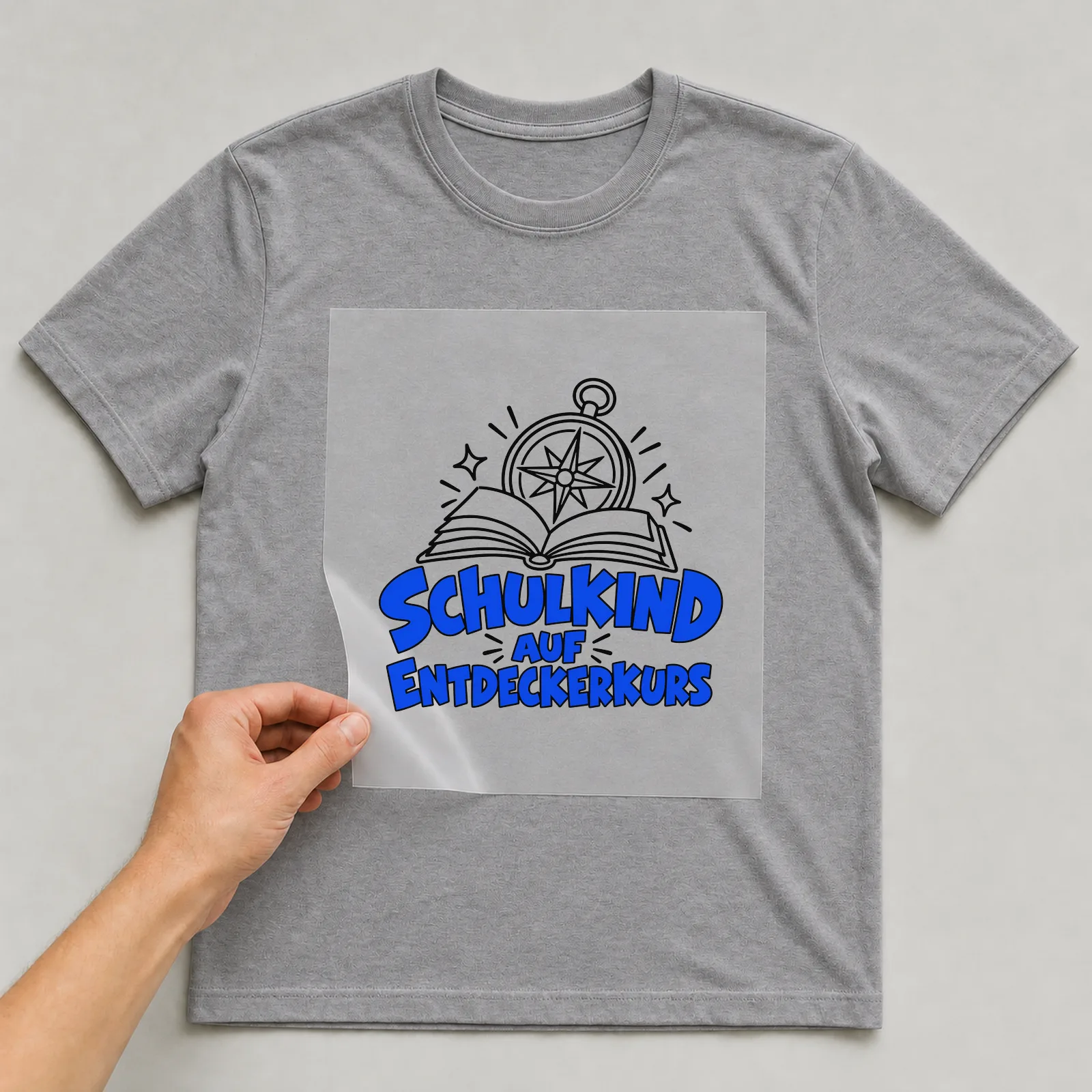 Bügelbild „Schulkind auf Entdeckerkurs“ auf grauem T-Shirt, Folie wird aufgelegt