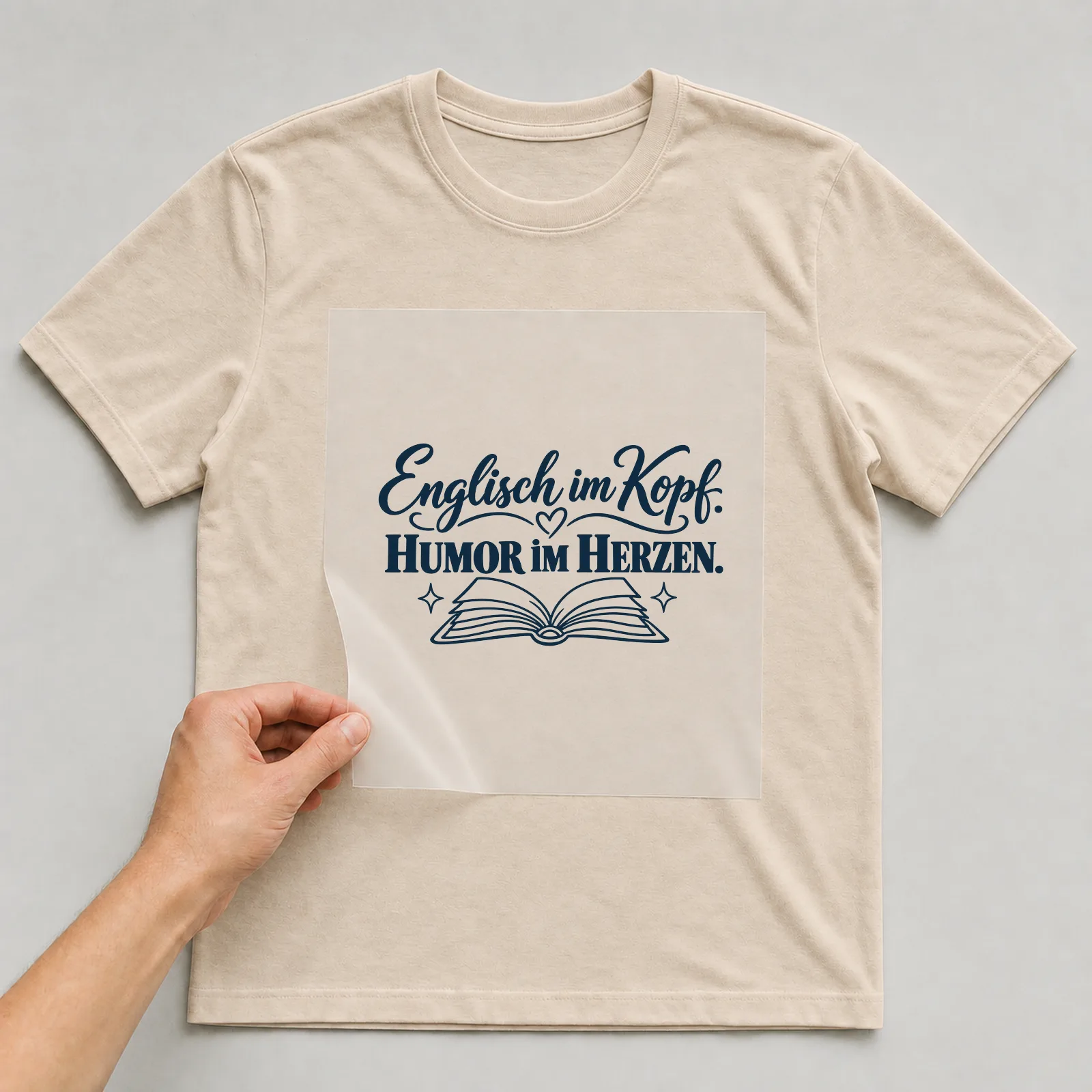 Bügelbild „Englisch im Kopf. Humor im Herzen.“ auf beigem T-Shirt, Folie wird aufgelegt