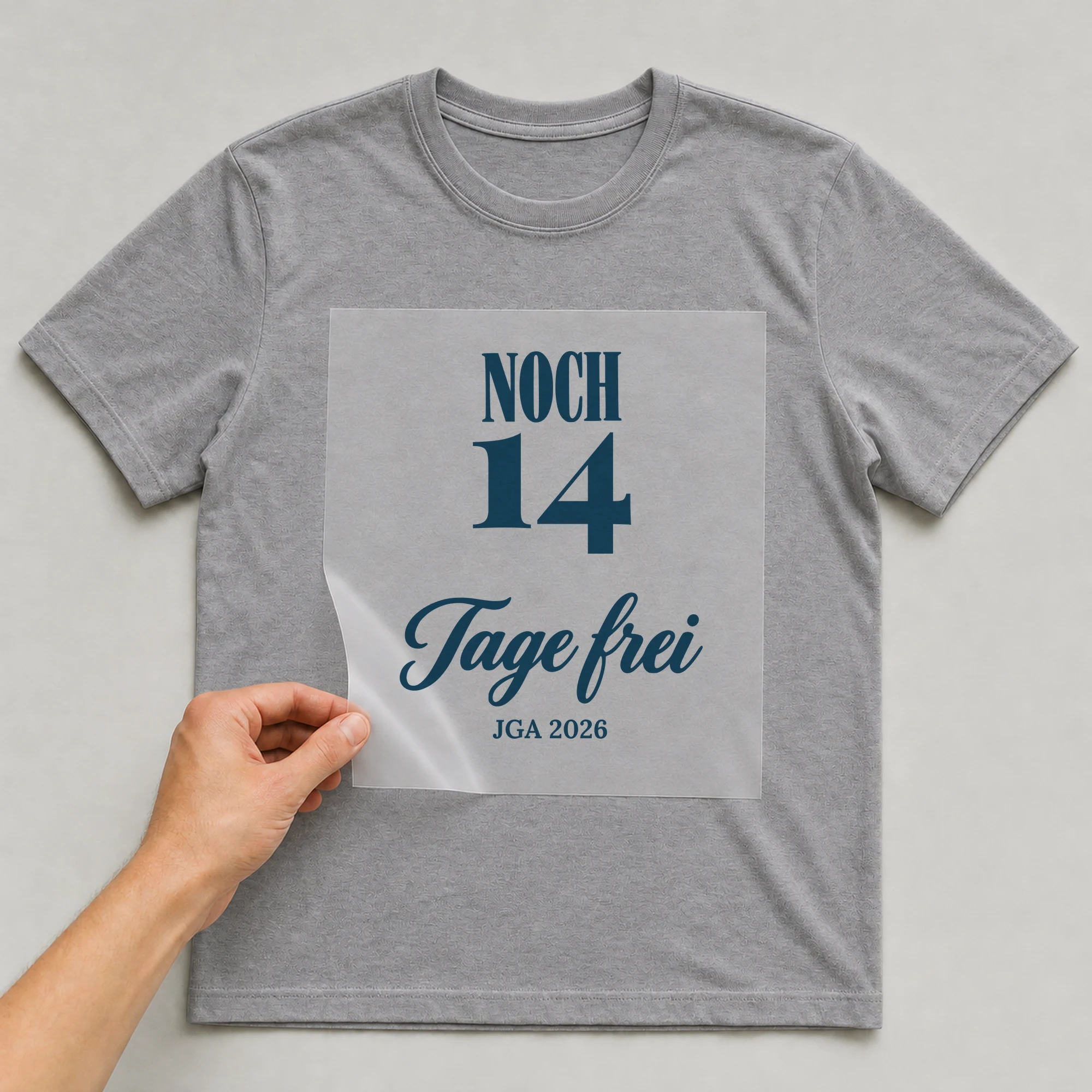 Bügelbild Noch Tage frei mit Zahl und Jahr auf grauem T-Shirt, Folie wird aufgelegt
