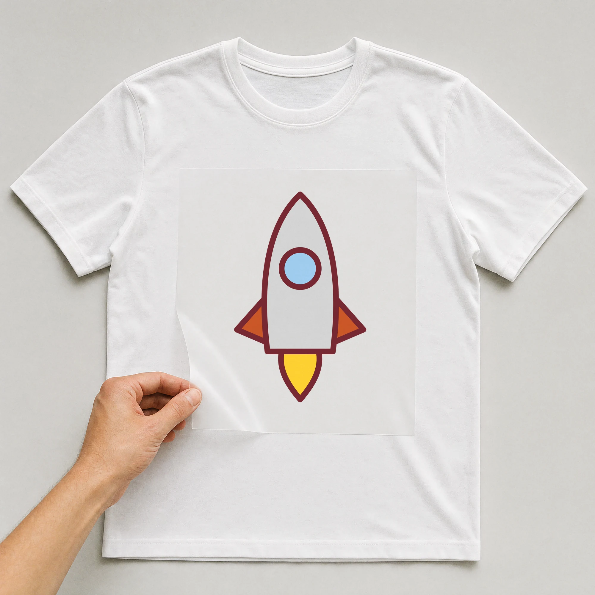 Bügelbild „Rakete“ auf weißem T-Shirt, Folie wird aufgelegt