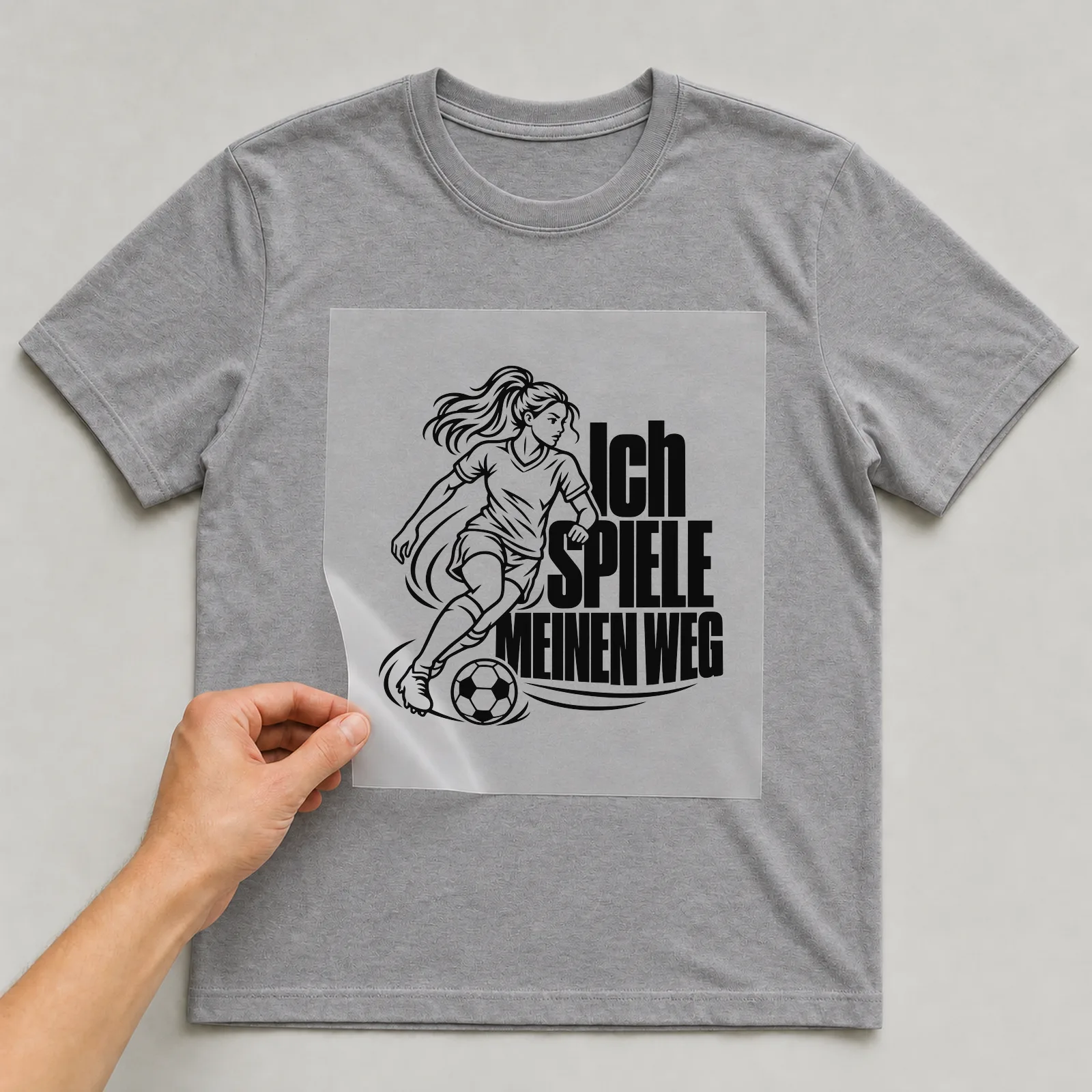 Bügelbild „Ich spiele meinen weg“ auf grauem T-Shirt, Folie wird aufgelegt