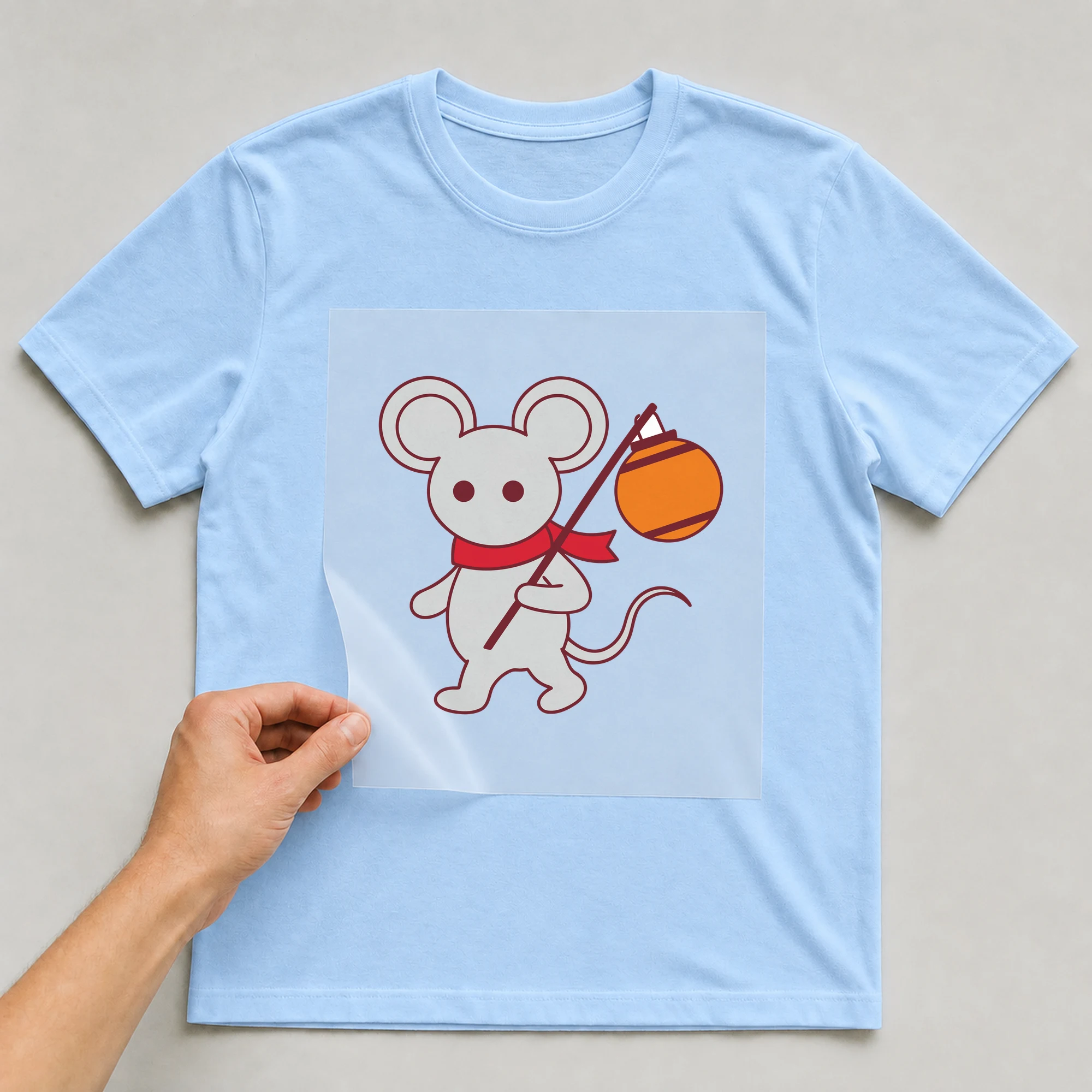 Bügelbild „Maus mit Laterne“ auf babyblauem T-Shirt, Folie wird aufgelegt