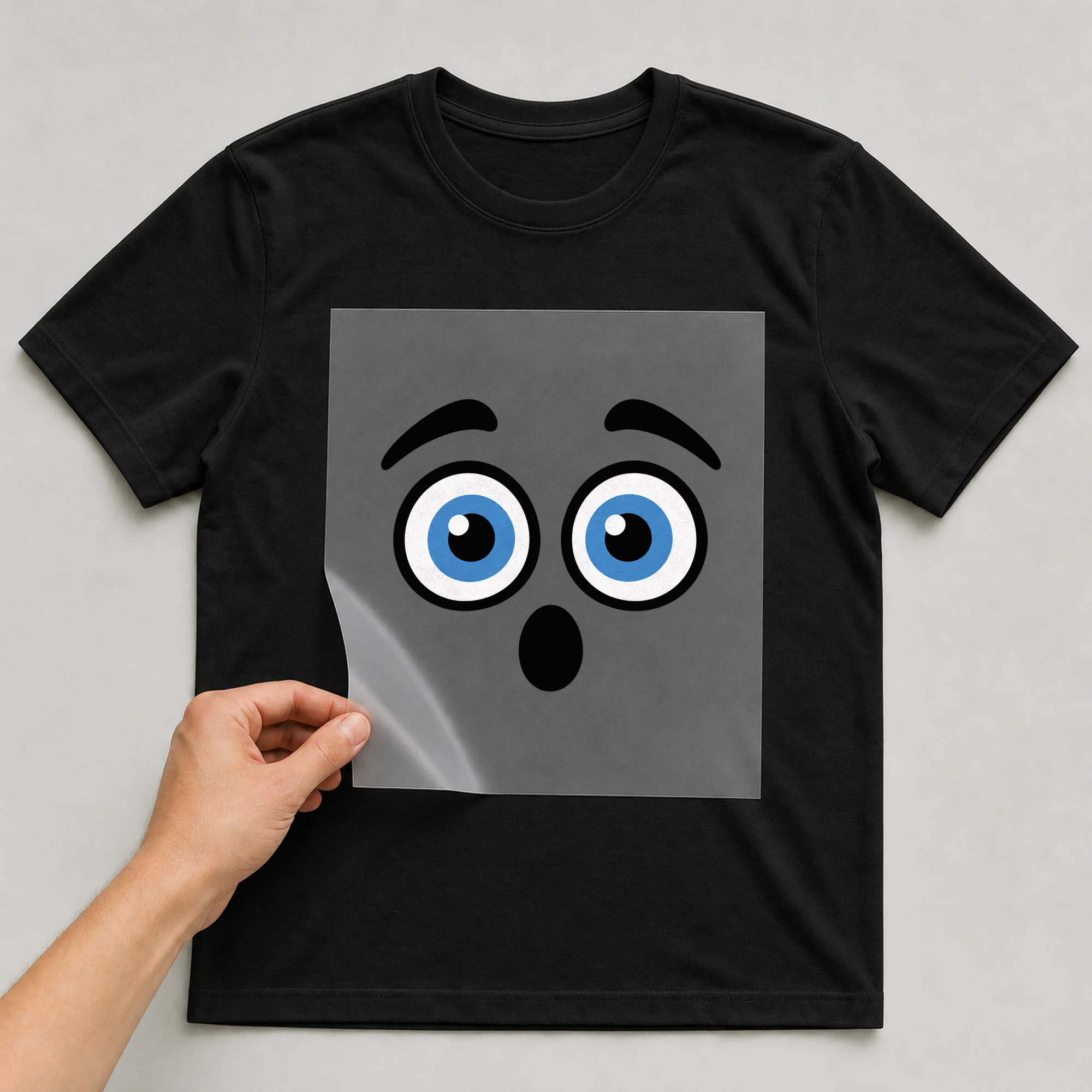 Bügelbild „Geschocktes Gesicht“ auf schwarzem T-Shirt, Folie wird aufgelegt