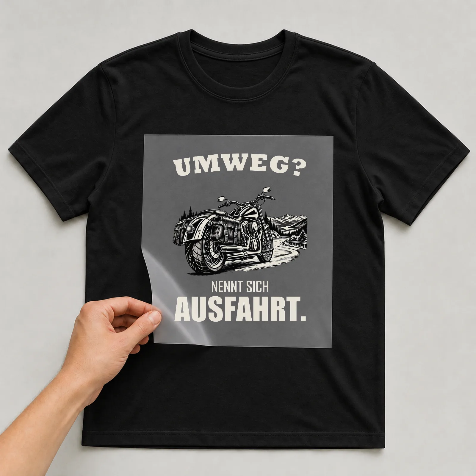 Bügelbild „Umweg? Nennt sich Ausfahrt.“ auf schwarzem T-Shirt, Folie wird aufgelegt