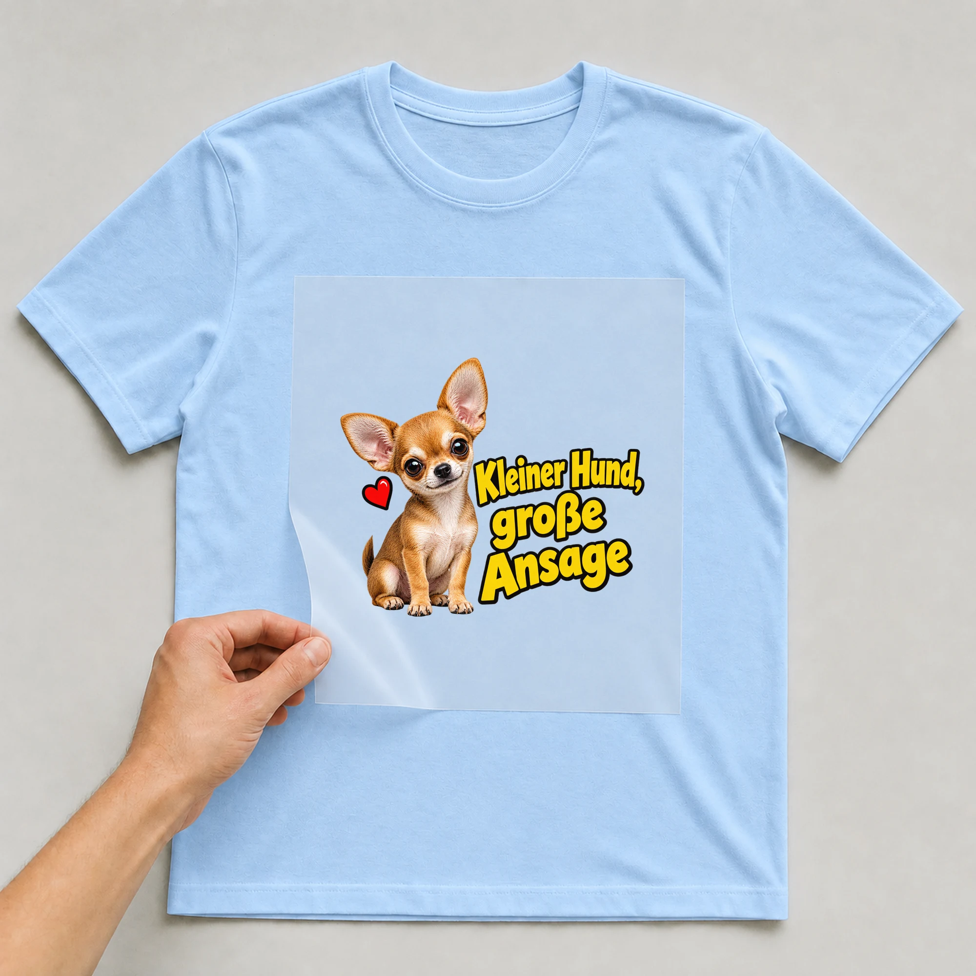 Bügelbild „Kleiner Hund, große Ansage“ auf babyblauem T-Shirt, Folie wird aufgelegt