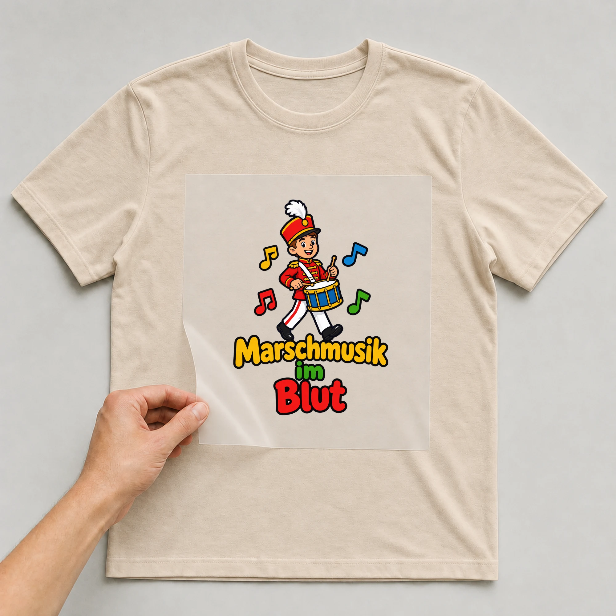 Bügelbild „Marschmusik im Blut“ auf beigem T-Shirt, Folie wird aufgelegt