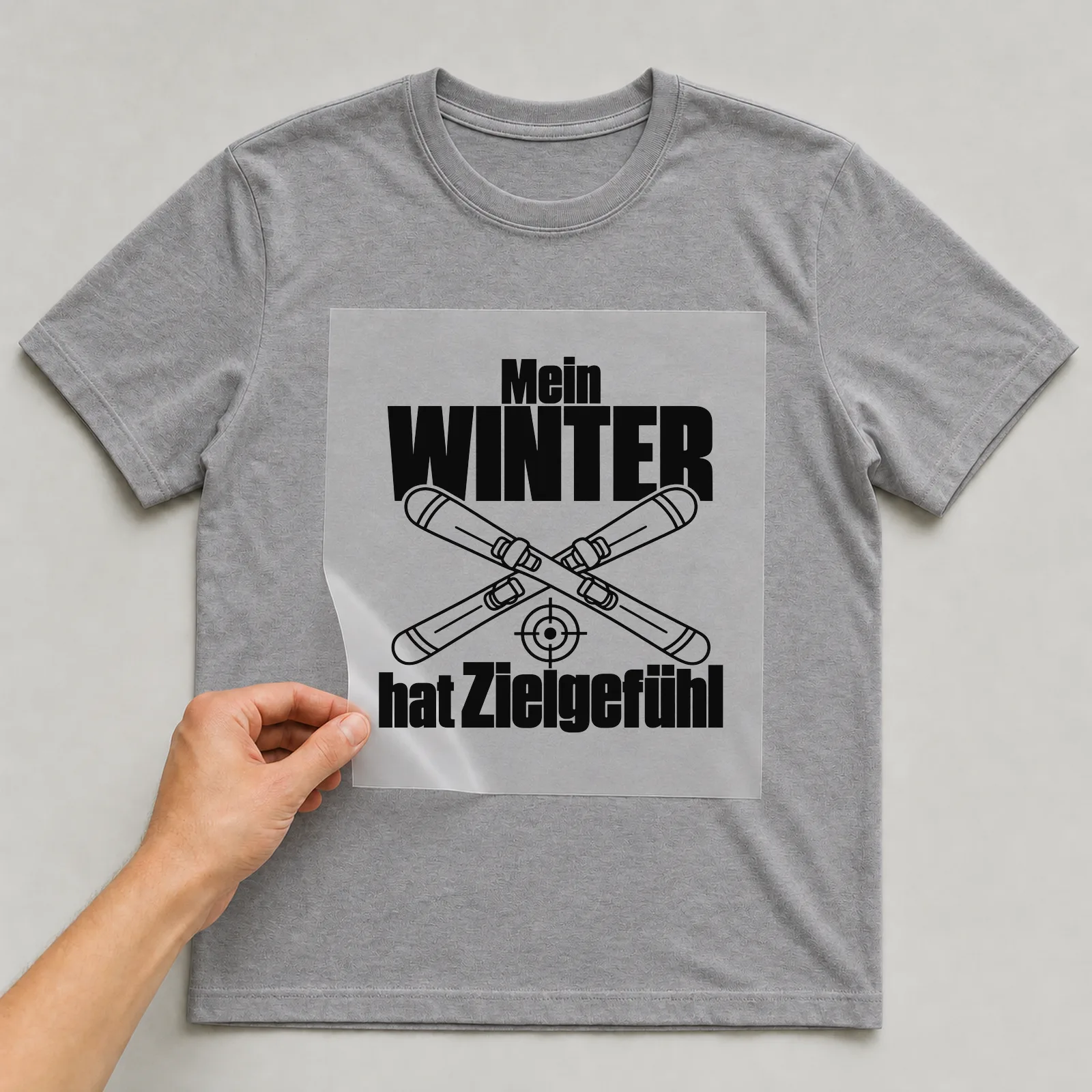 Bügelbild „Mein Winter hat Zielgefühl“ auf grauem T-Shirt, Folie wird aufgelegt