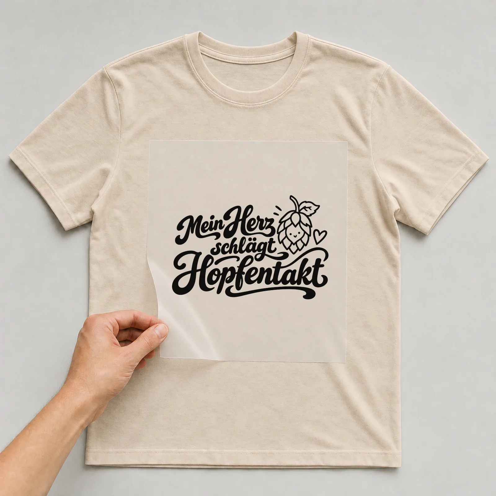 Bügelbild „Mein Herz schlägt Hopfentakt“ auf beigem T-Shirt, Folie wird aufgelegt