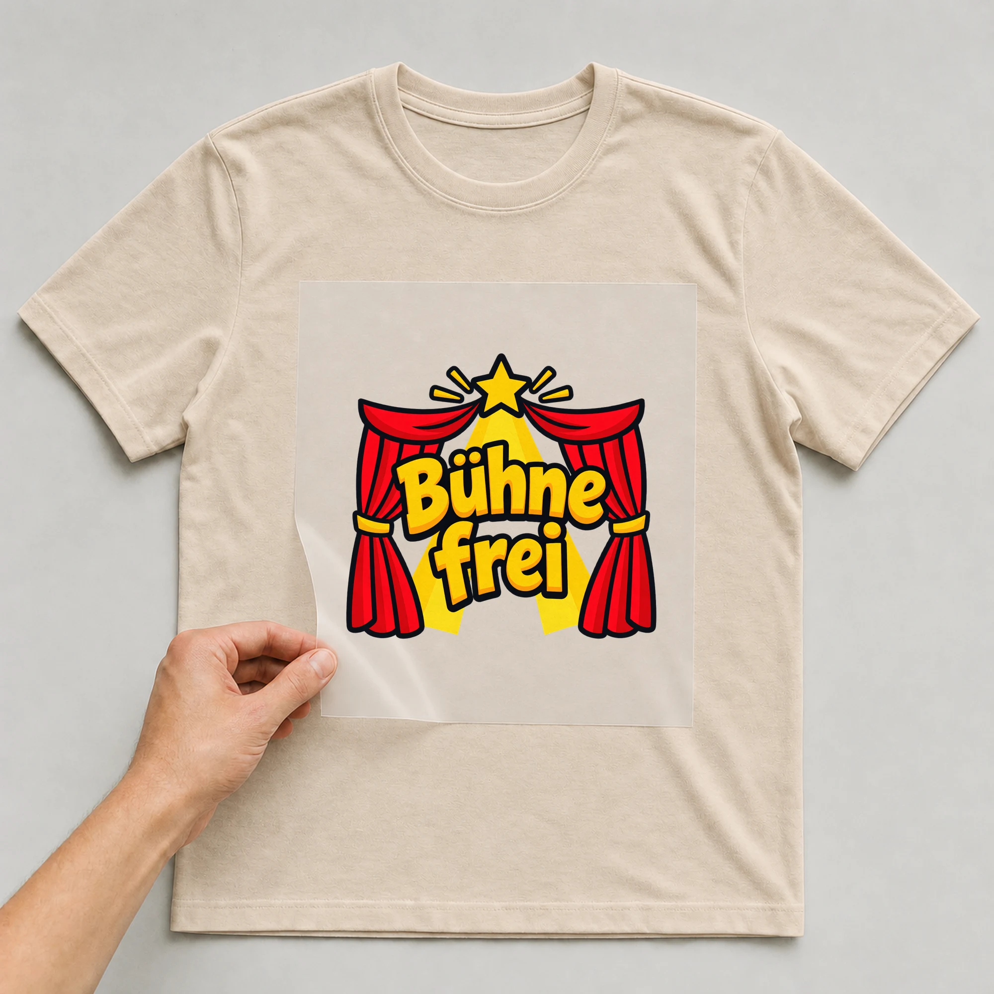 Bügelbild „Bühne frei“ auf beigem T-Shirt, Folie wird aufgelegt