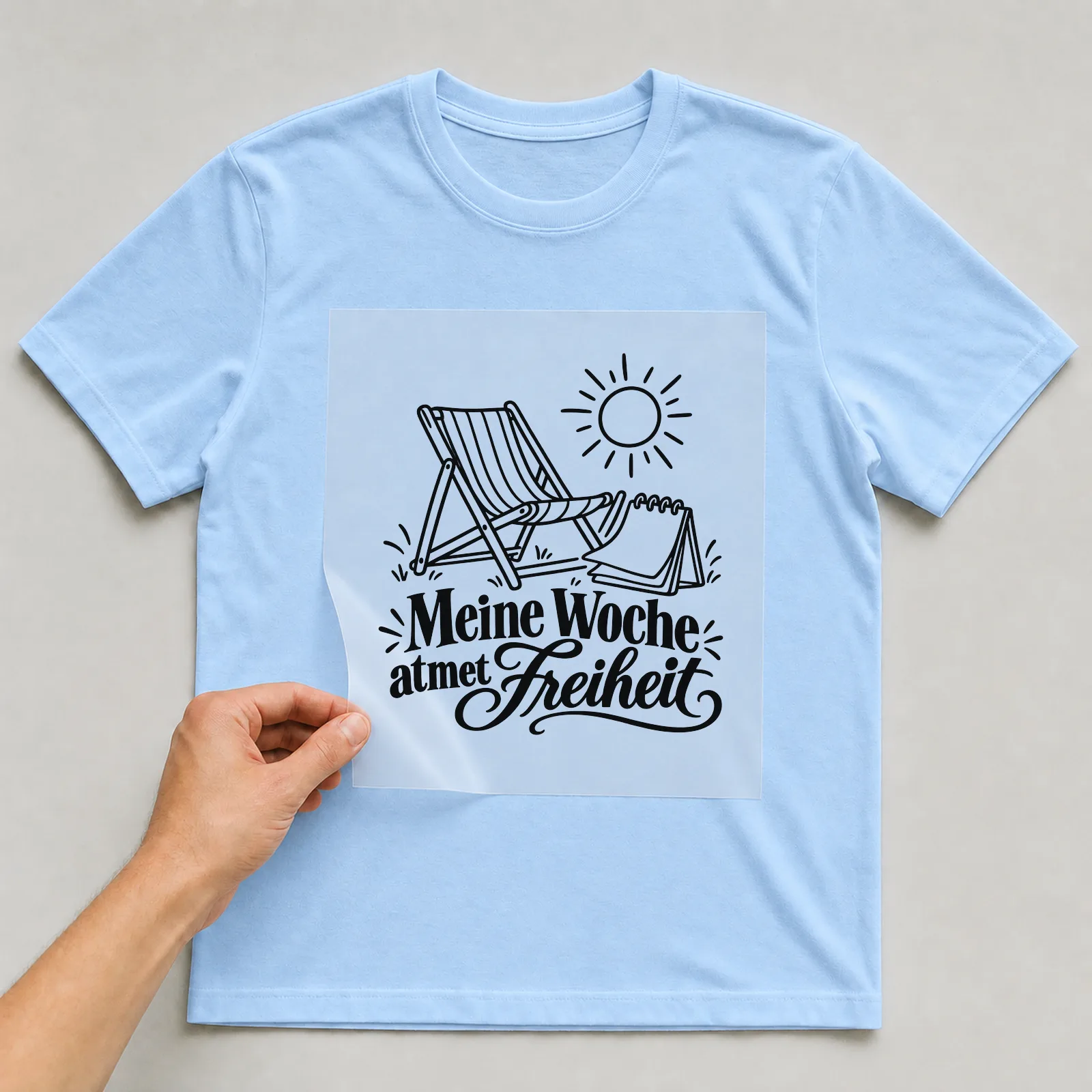 Bügelbild „Meine Woche atmet Freiheit“ auf hellblauem T-Shirt, Folie wird aufgelegt