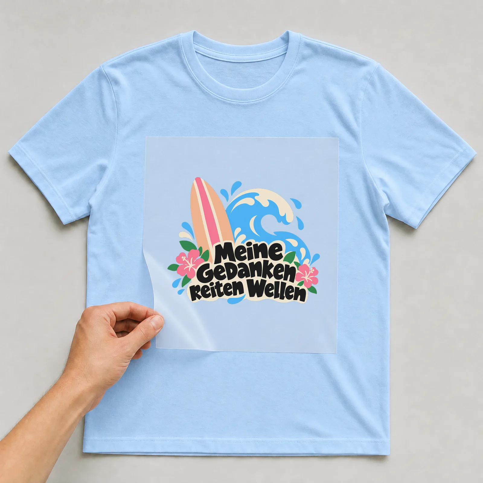 Bügelbild „Meine Gedanken reiten Wellen“ auf hellblauem T-Shirt, Folie wird aufgelegt