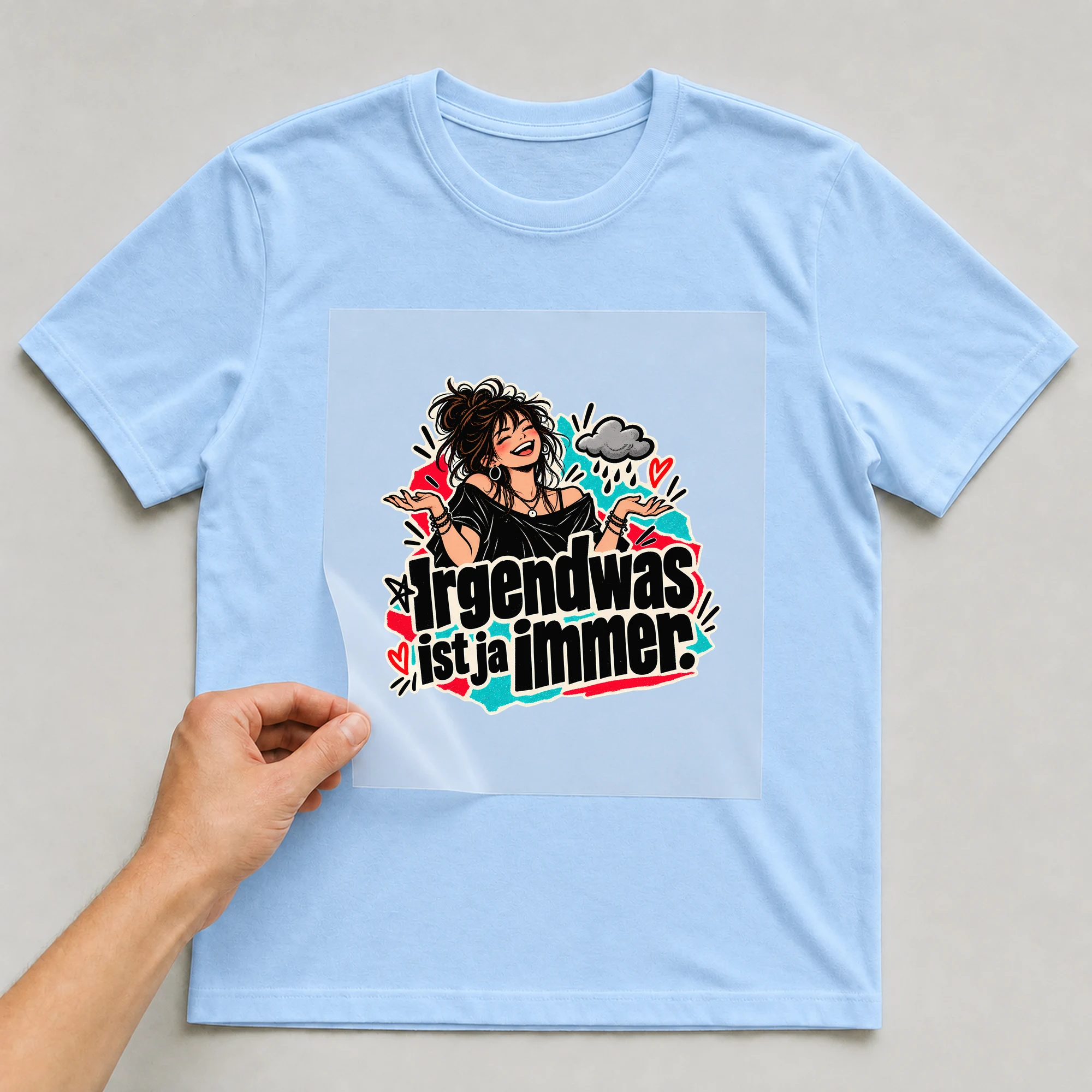Bügelbild „Irgendwas ist ja immer.“ auf babyblauem T-Shirt, Folie wird aufgelegt