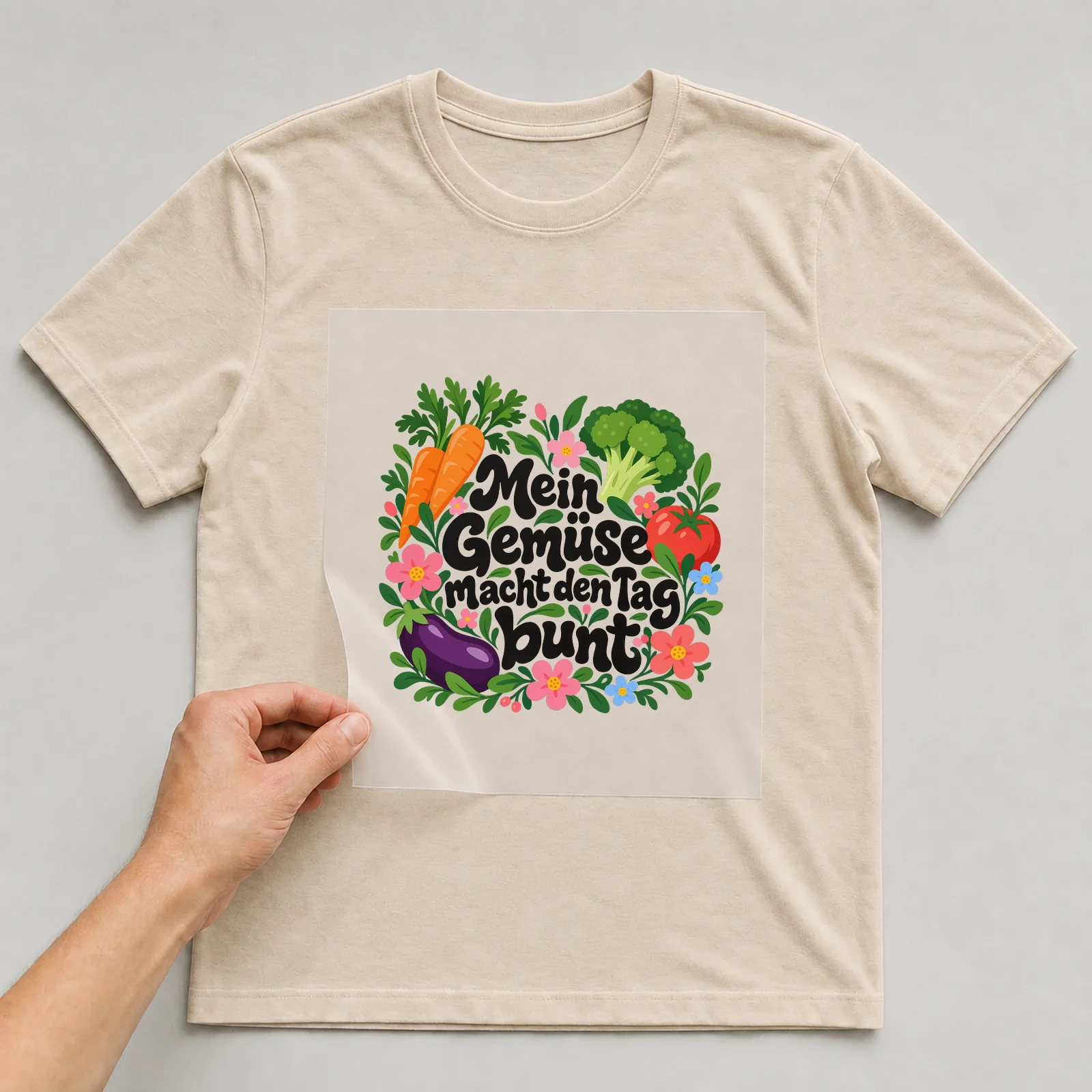 Bügelbild „Mein Gemüse macht den Tag bunt“ auf beigem T-Shirt, Folie wird aufgelegt