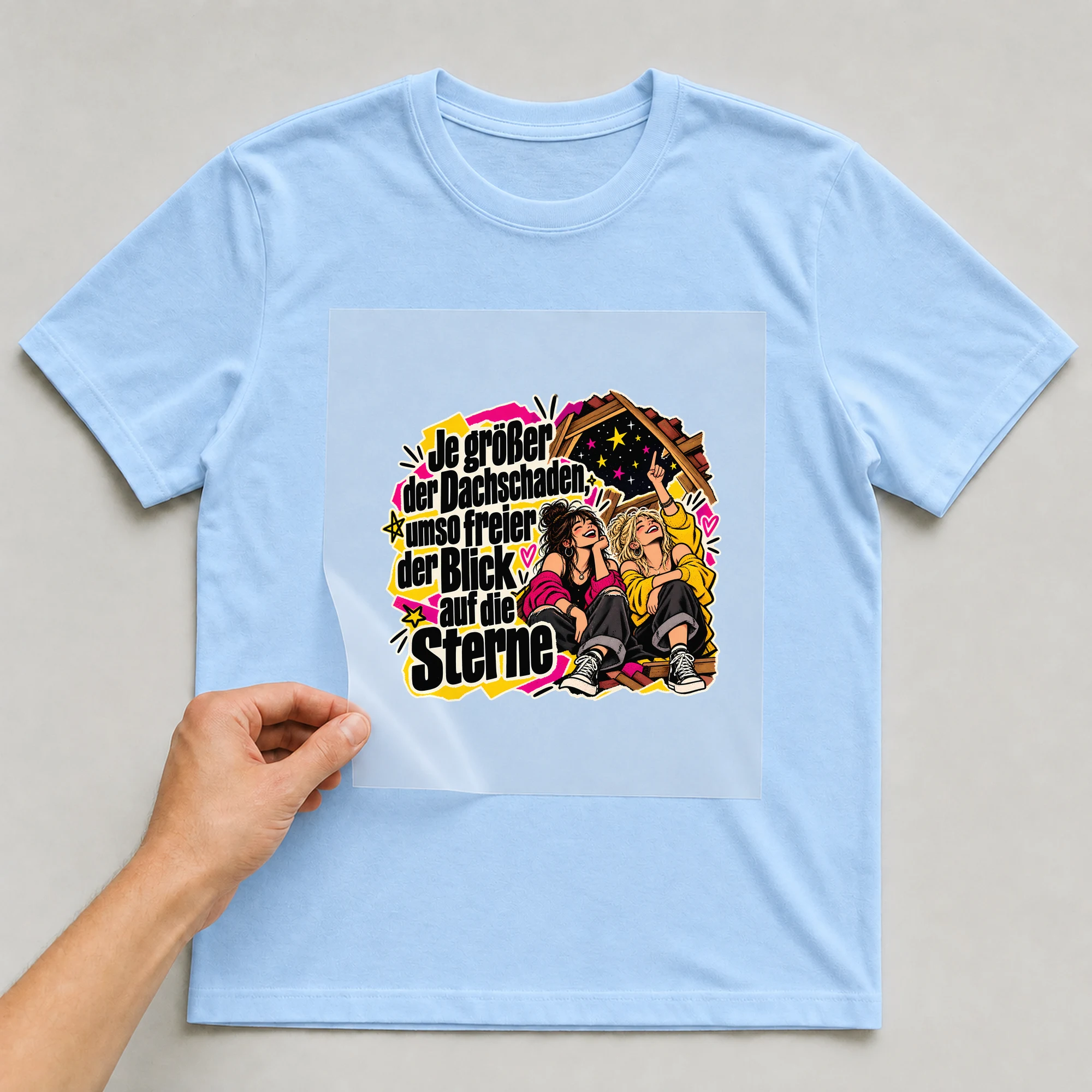 Bügelbild „Je größer der Dachschaden, umso freier der Blick“ auf babyblauem T-Shirt, Folie wird aufgelegt