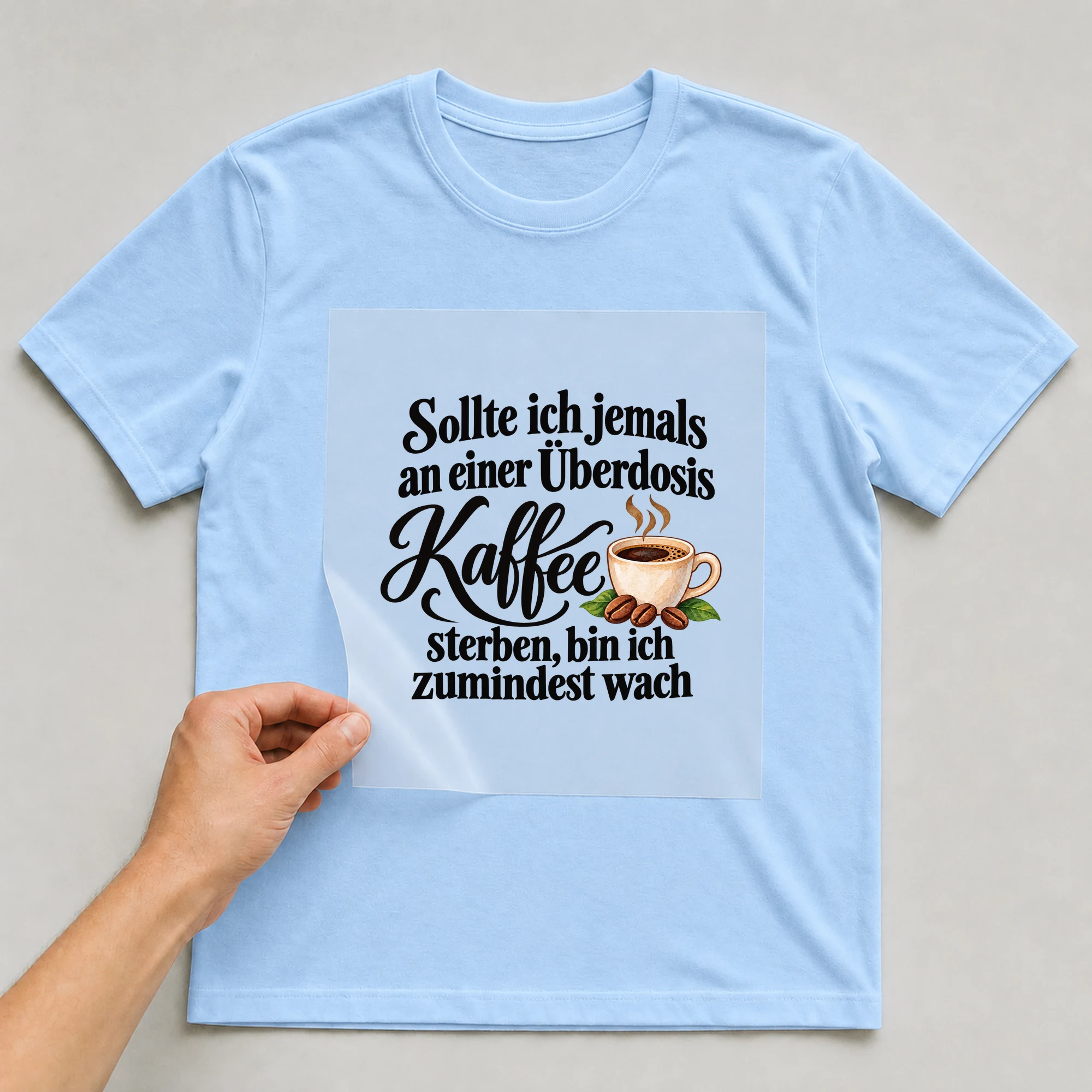 Bügelbild „Sollte ich jemals an einer Überdosis Kaffee sterben, bin ich zumindest wach“ auf babyblauem T-Shirt, Folie wird aufgelegt