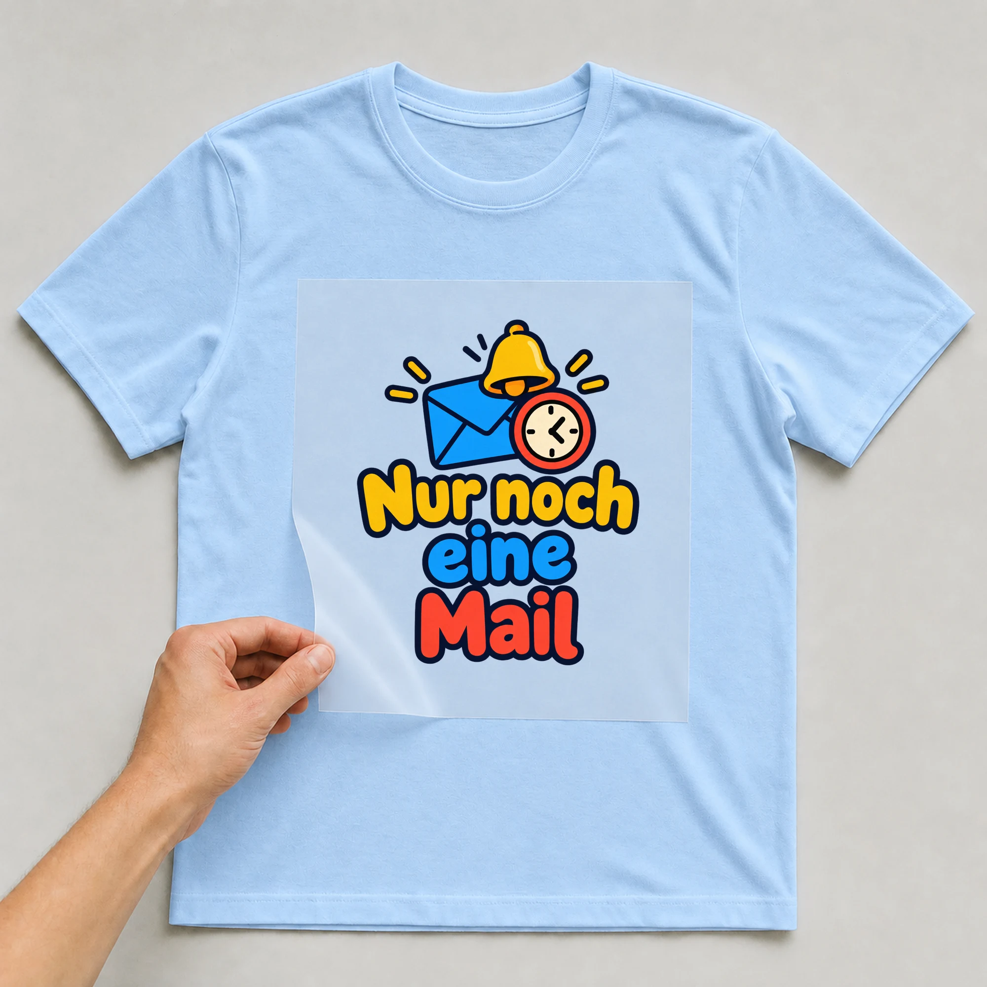 Bügelbild „Nur noch eine Mail“ auf babyblauem T-Shirt, Folie wird aufgelegt