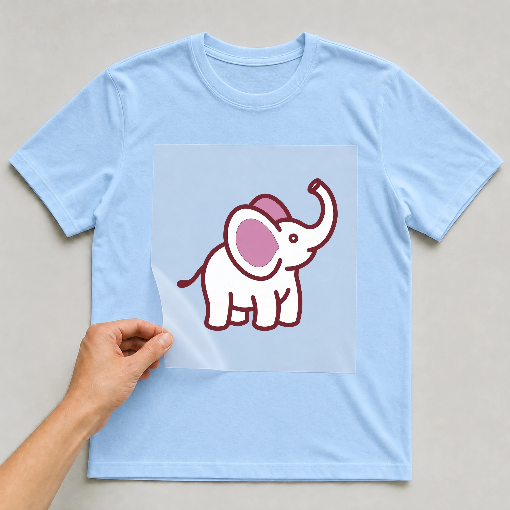 Bügelbild „Elefant“ auf babyblauem T-Shirt, Folie wird aufgelegt