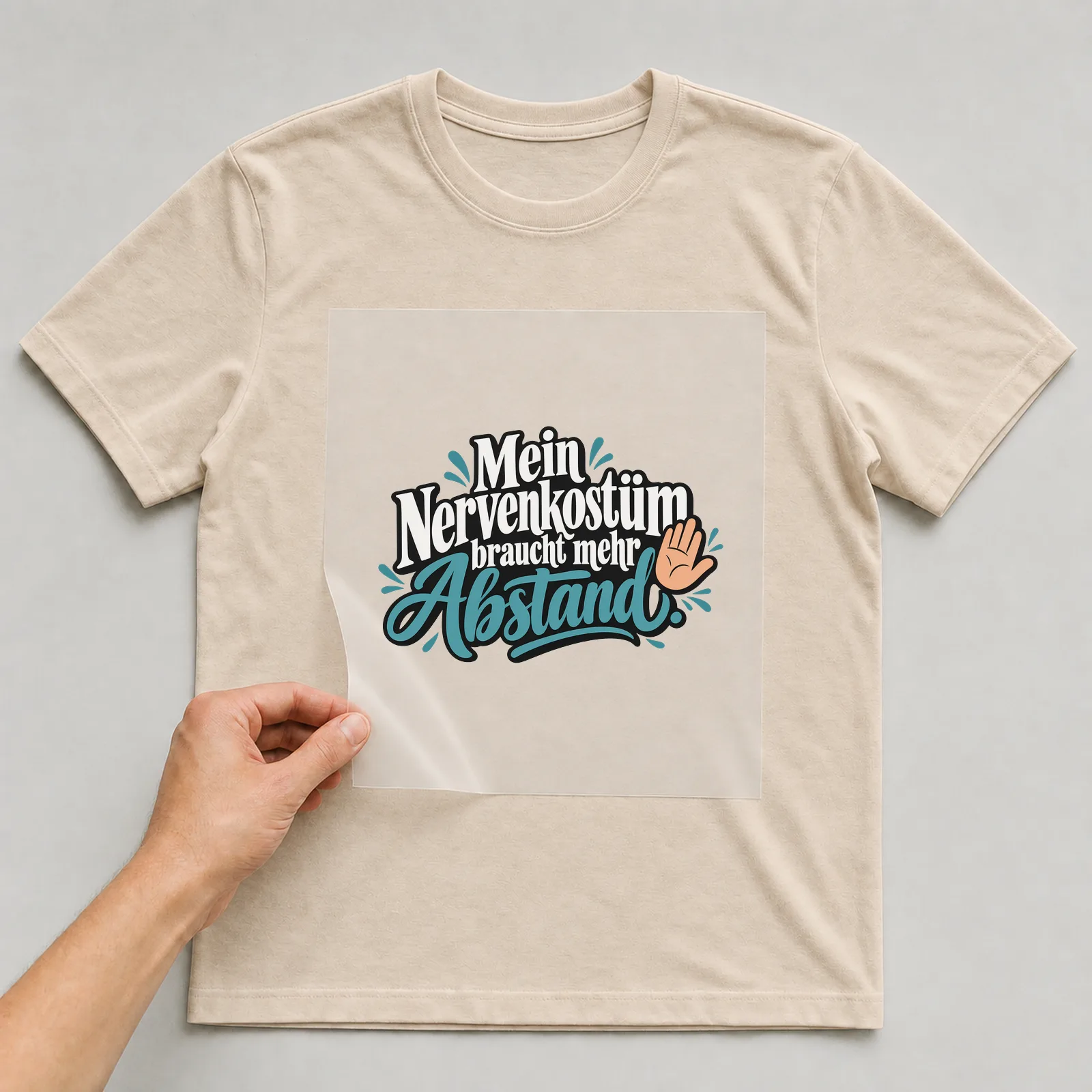 Bügelbild „Mein Nervenkostüm braucht mehr Abstand“ auf beigem T-Shirt, Folie wird aufgelegt