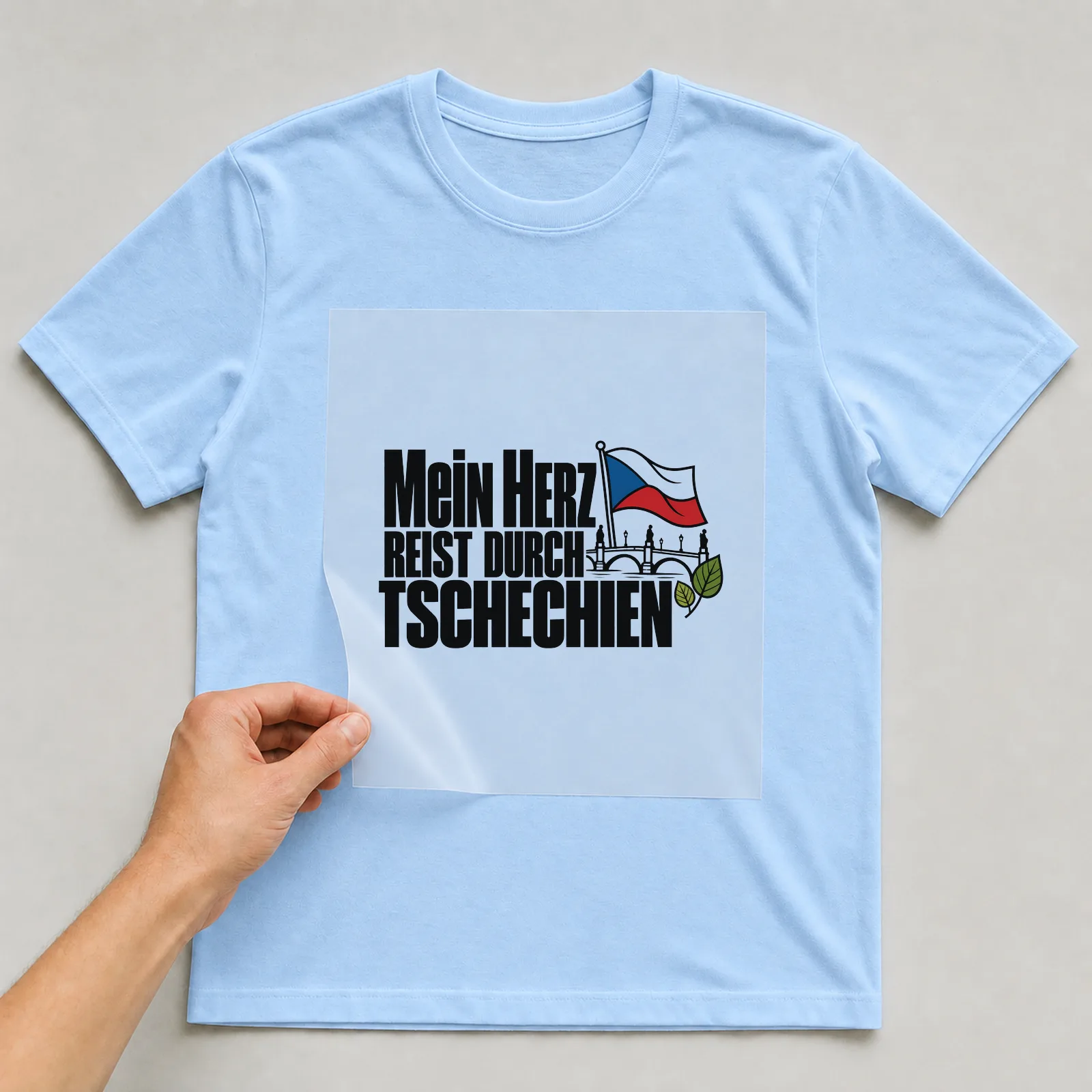 Bügelbild „Mein Herz reist durch Tschechien“ auf hellblauem T-Shirt, Folie wird aufgelegt