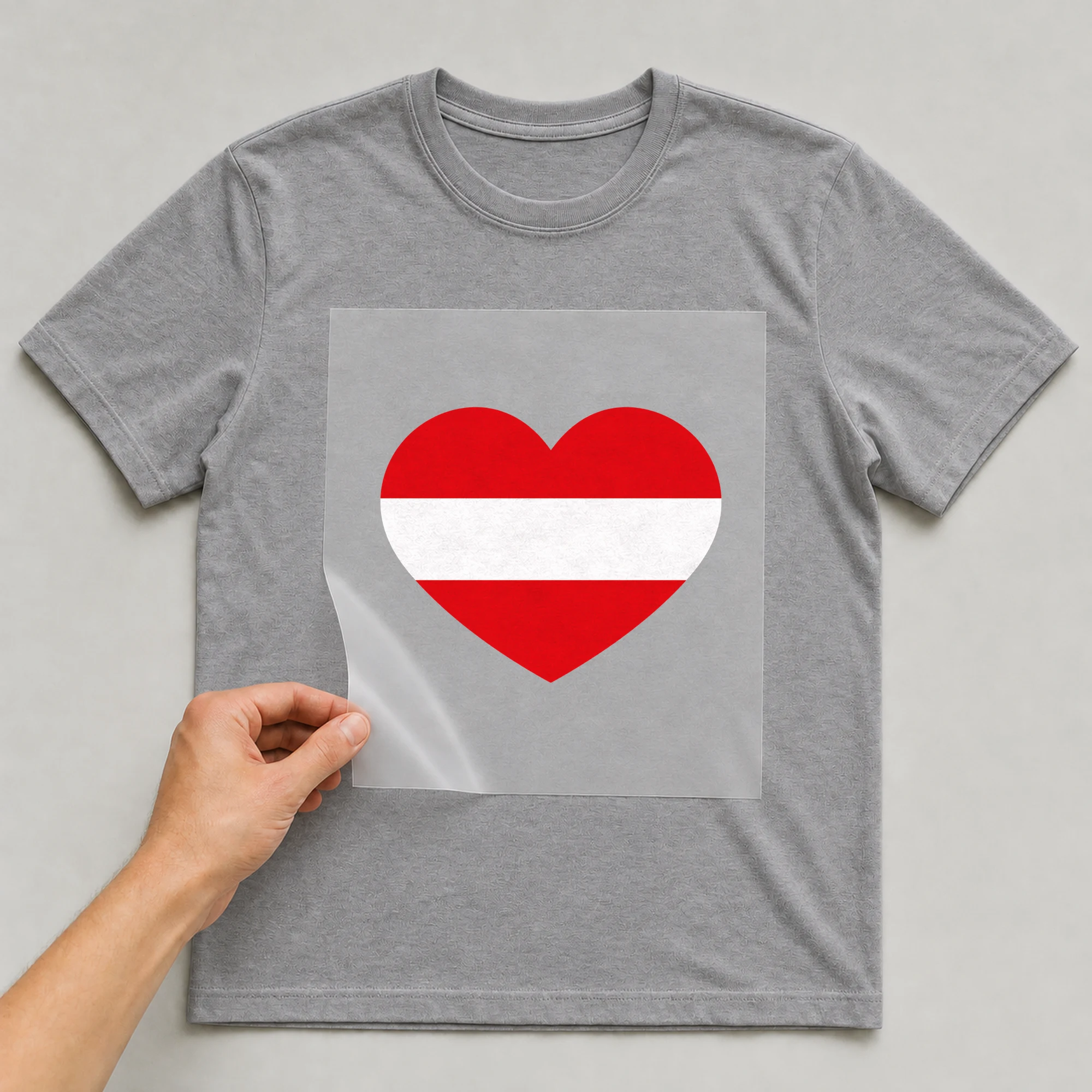 Bügelbild „Herz Flagge Österreich“ auf grauem T-Shirt, Folie wird aufgelegt
