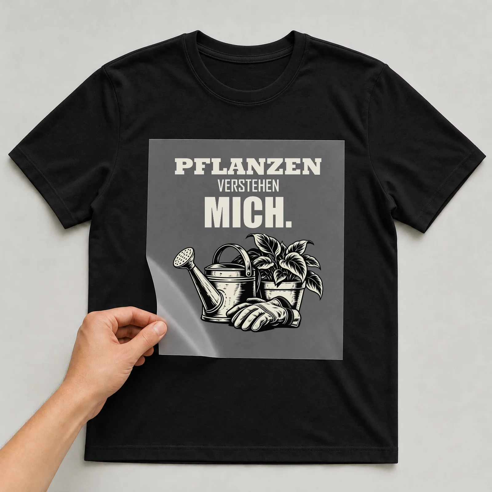 Bügelbild „Pflanzen verstehen mich“ auf schwarzem T-Shirt, Folie wird aufgelegt