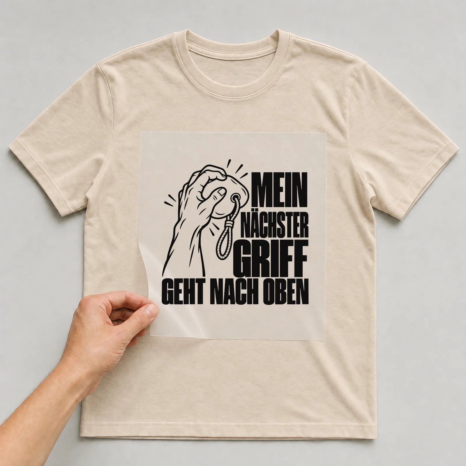 Bügelbild „Mein nächster Griff geht nach Oben“ auf beigem T-Shirt, Folie wird aufgelegt