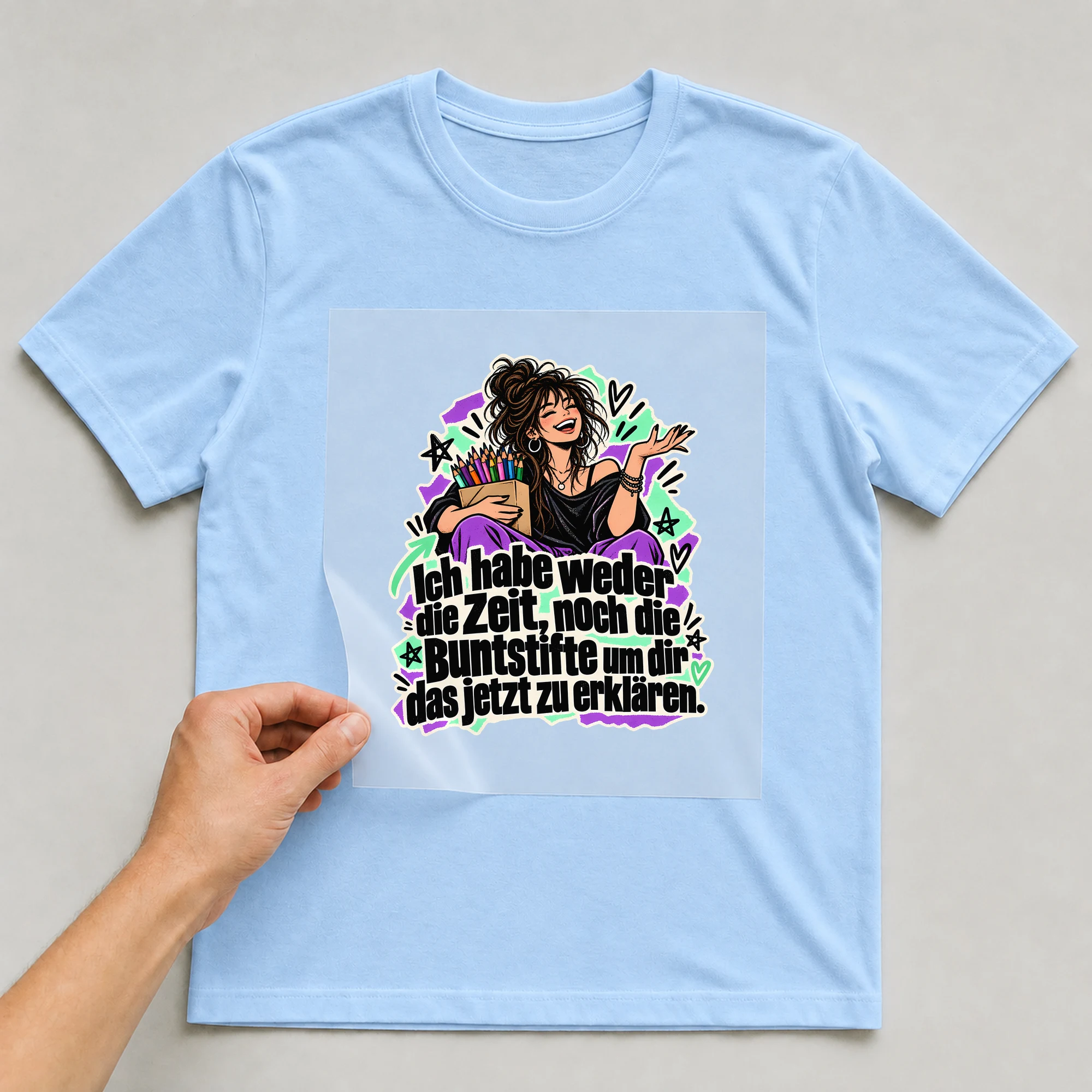 Bügelbild „Ich habe weder die Zeit, noch die Buntstifte“ auf babyblauem T-Shirt, Folie wird aufgelegt