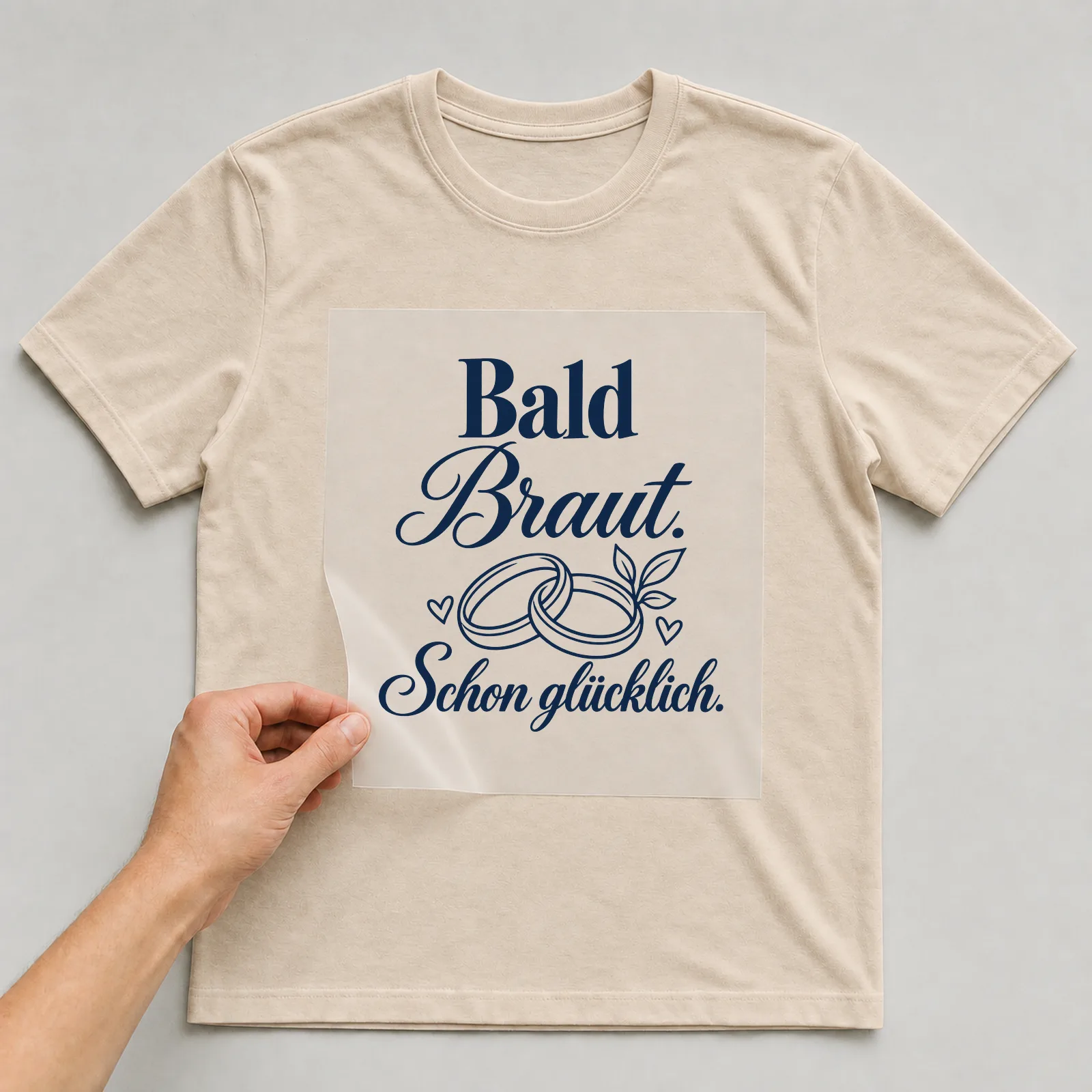 Bügelbild „Bald Braut. Schon glücklich.“ auf beigem T-Shirt, Folie wird aufgelegt