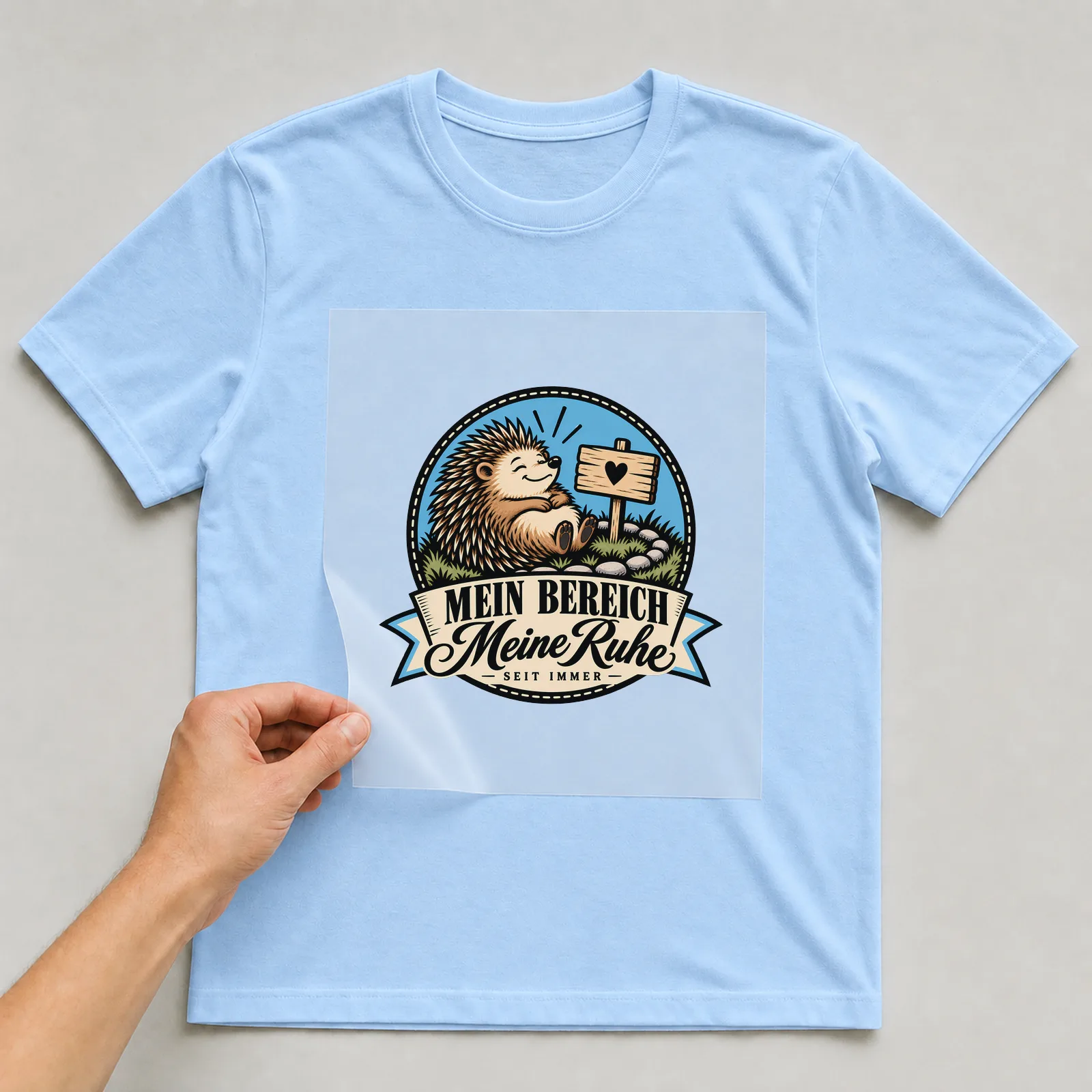 Bügelbild „Mein Bereich Meine Ruhe Seit immer“ auf hellblauem T-Shirt, Folie wird aufgelegt