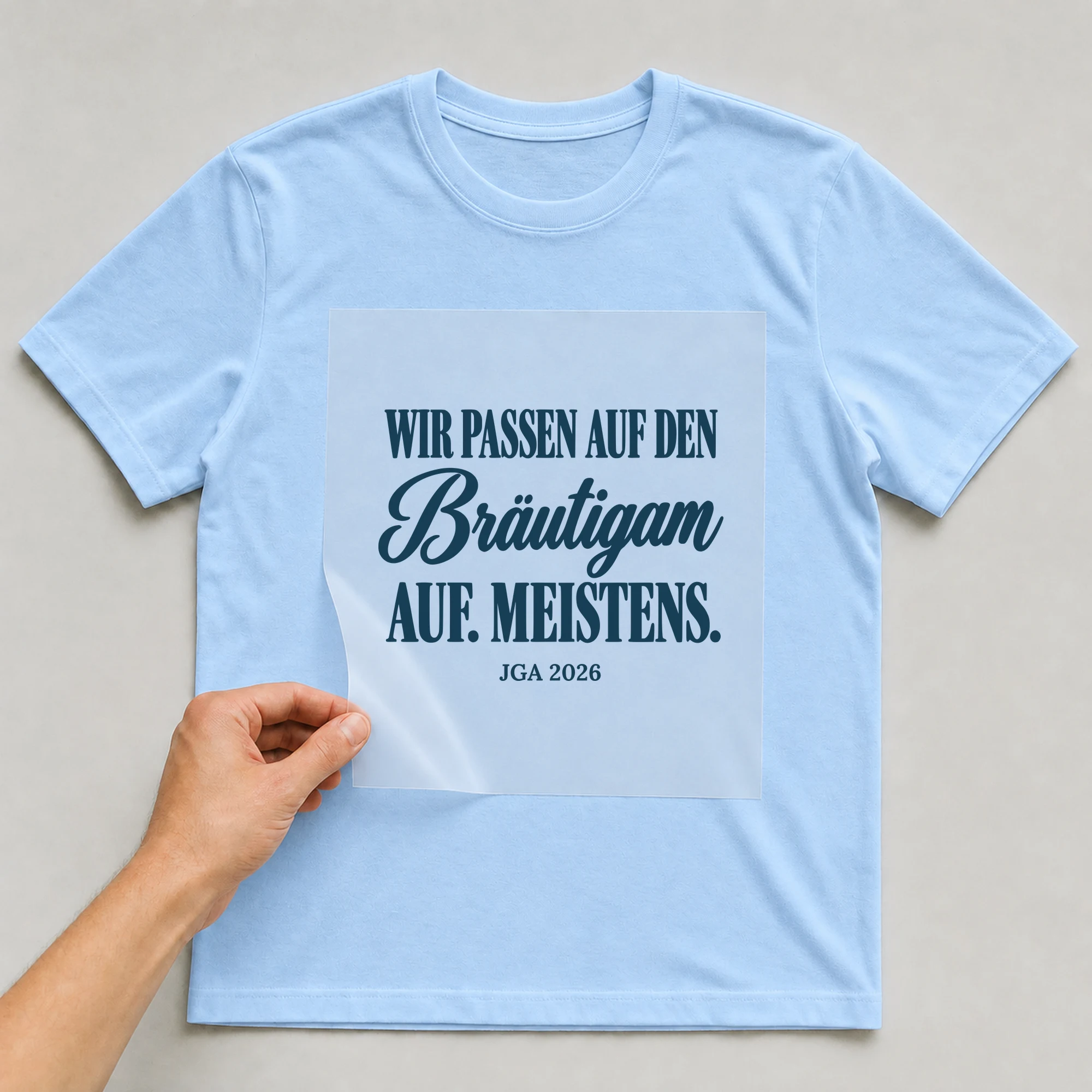 Bügelbild Wir passen auf den Bräutigam auf mit Jahr auf hellblauem T-Shirt, Folie wird aufgelegt