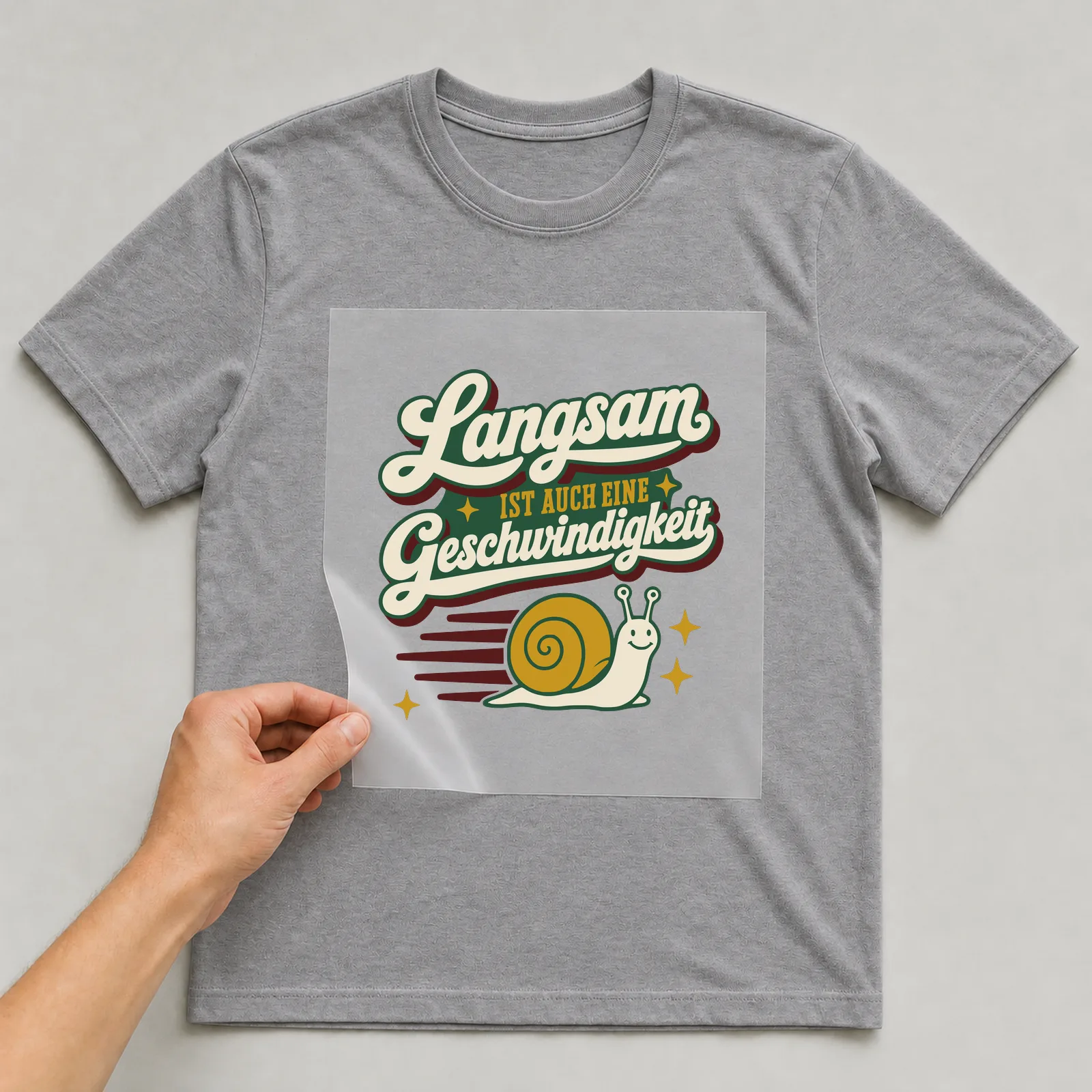Bügelbild Langsam ist auch eine Geschwindigkeit auf grauem T-Shirt, Folie wird aufgelegt