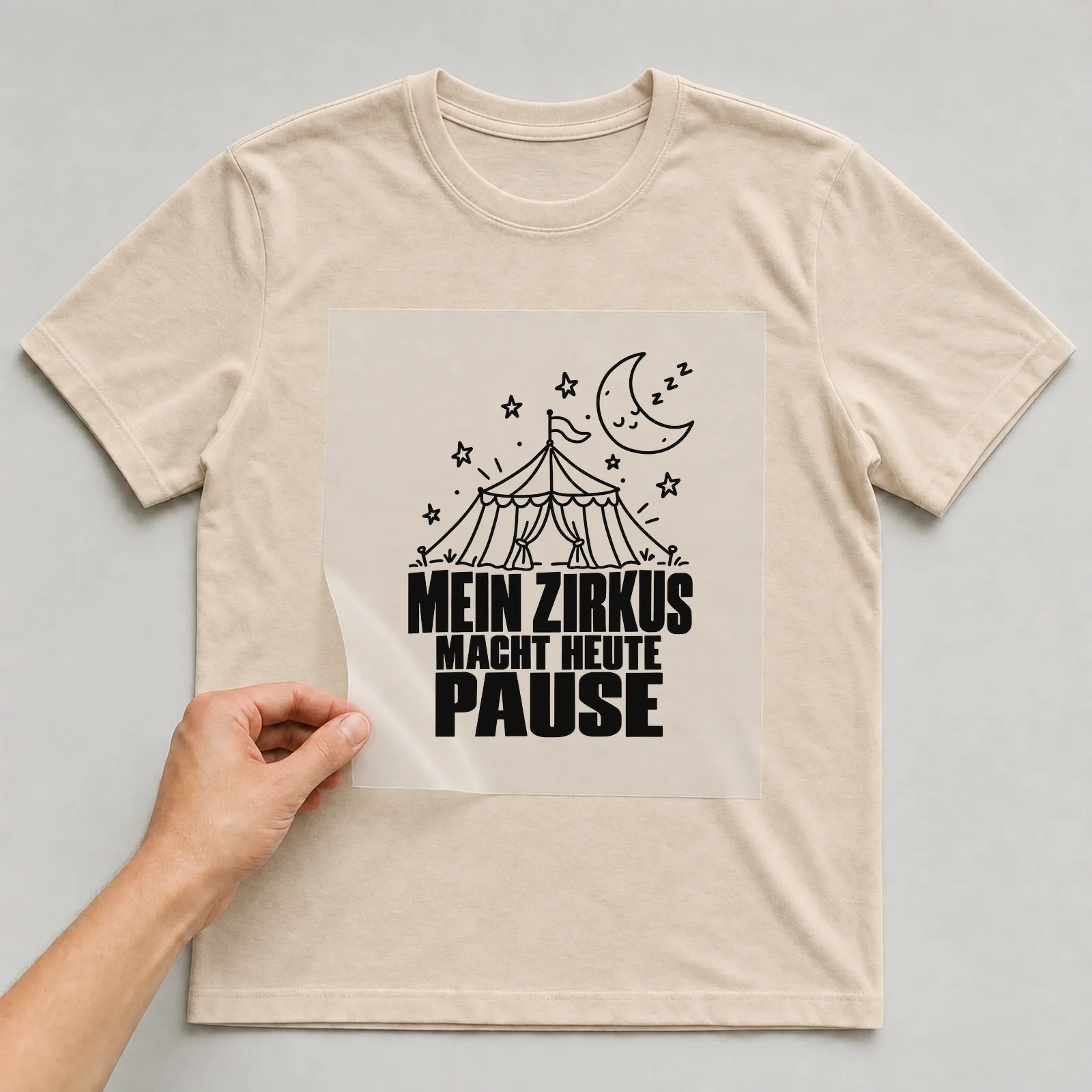 Bügelbild „Mein Zirkus macht heute Pause“ auf beigem T-Shirt, Folie wird aufgelegt