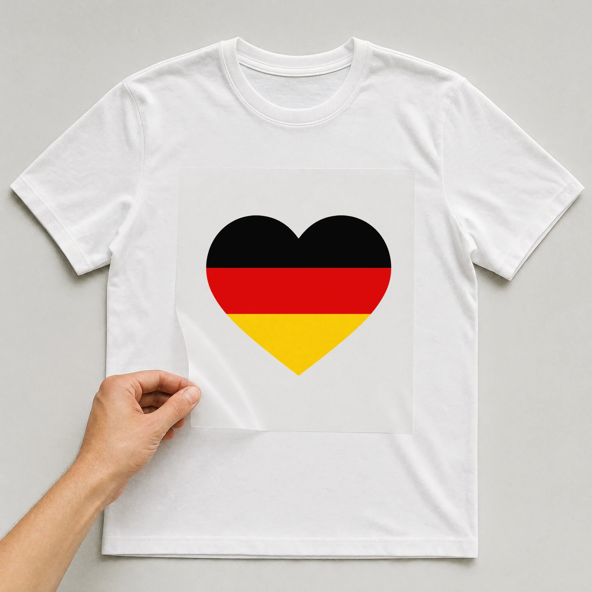 Bügelbild „Deutschland Fahne Herz“ auf weißem T-Shirt, Folie wird aufgelegt
