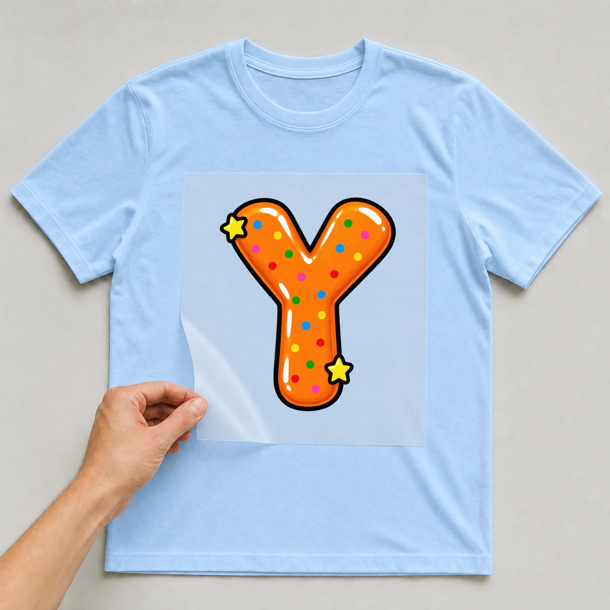 Bügelbild „Buchstabe Y im Comic-Ballon-Stil“ auf babyblauem T-Shirt, Folie wird aufgelegt