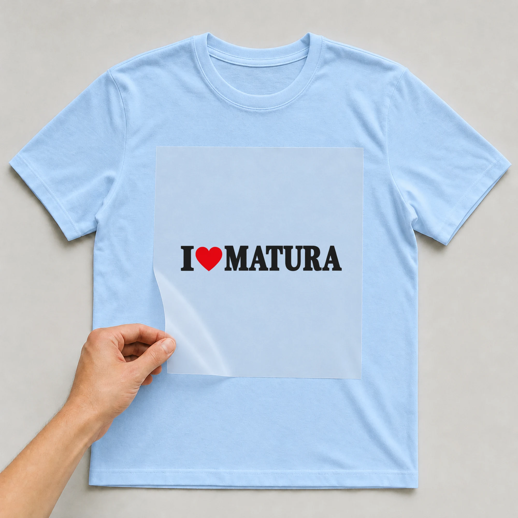 Bügelbild „I Matura“ auf babyblauem T-Shirt, Folie wird aufgelegt