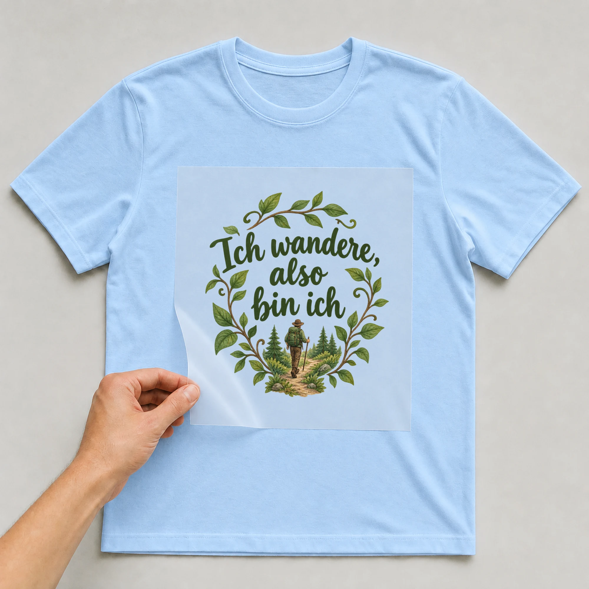 Bügelbild „Ich wandere also bin ich“ auf babyblauem T-Shirt, Folie wird aufgelegt