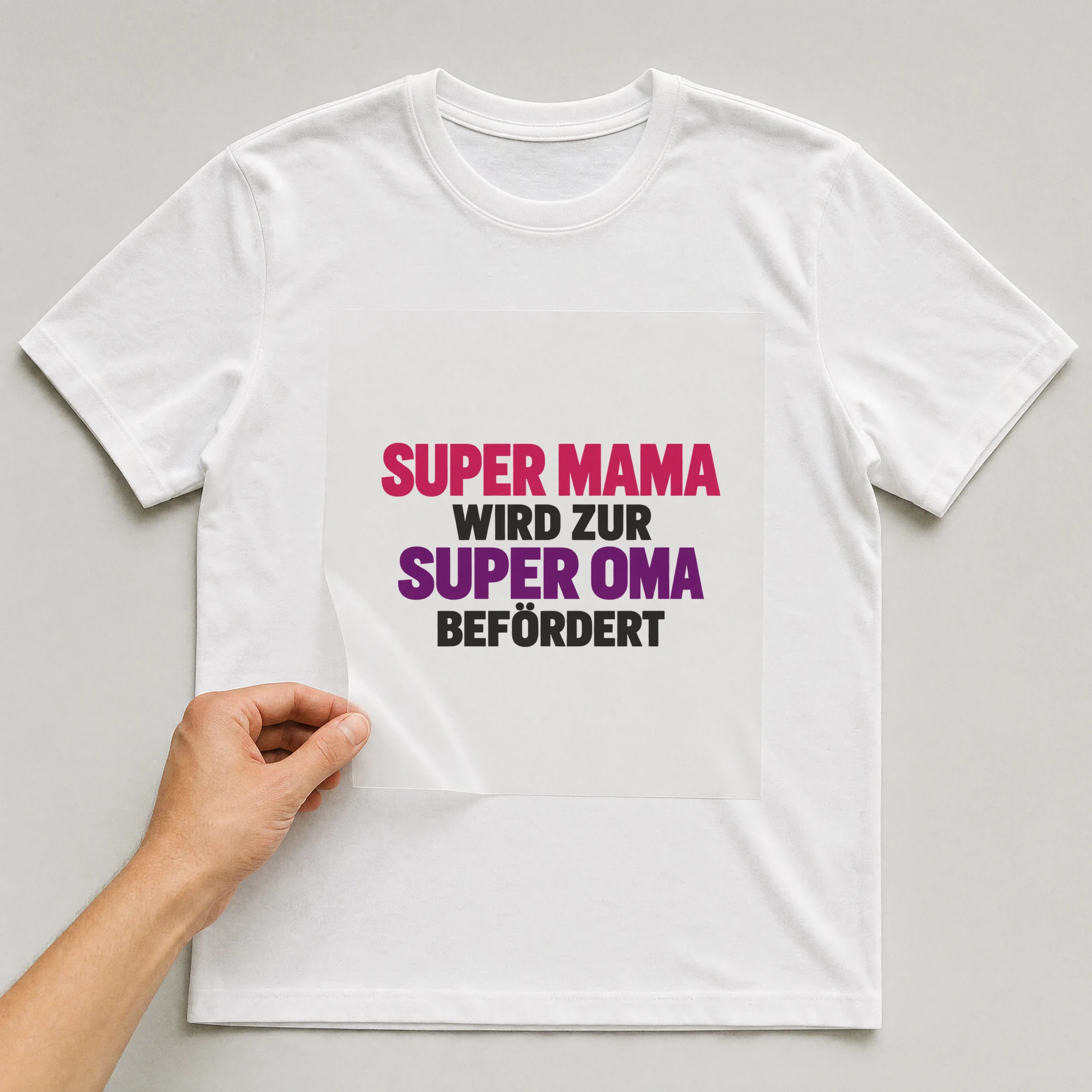 Bügelbild „Super Mama wird zur super Oma befördert“ auf weißem T-Shirt, Folie wird aufgelegt