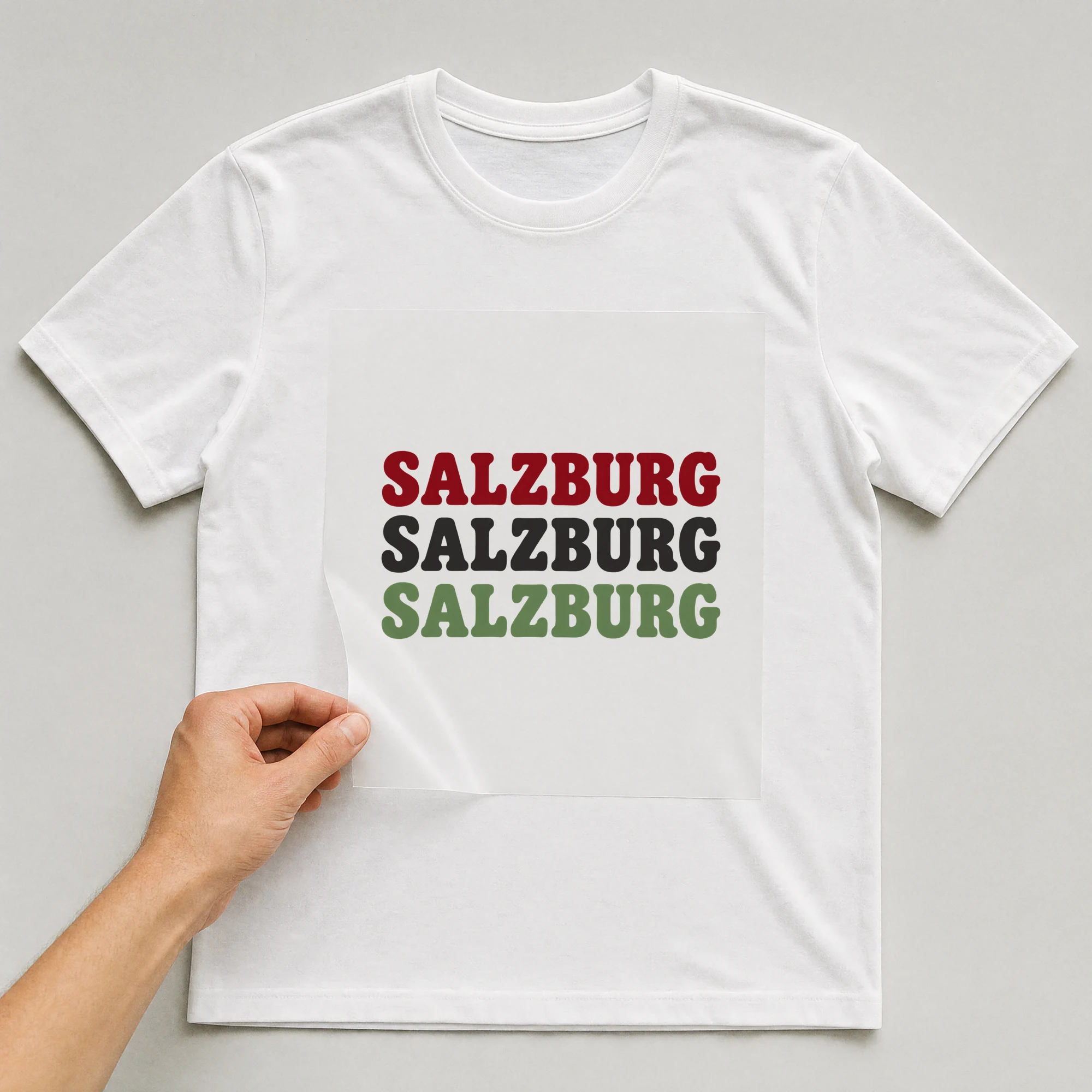 Bügelbild „SALZBURG SALZBURG SALZBURG“ auf weißem T-Shirt, Folie wird aufgelegt
