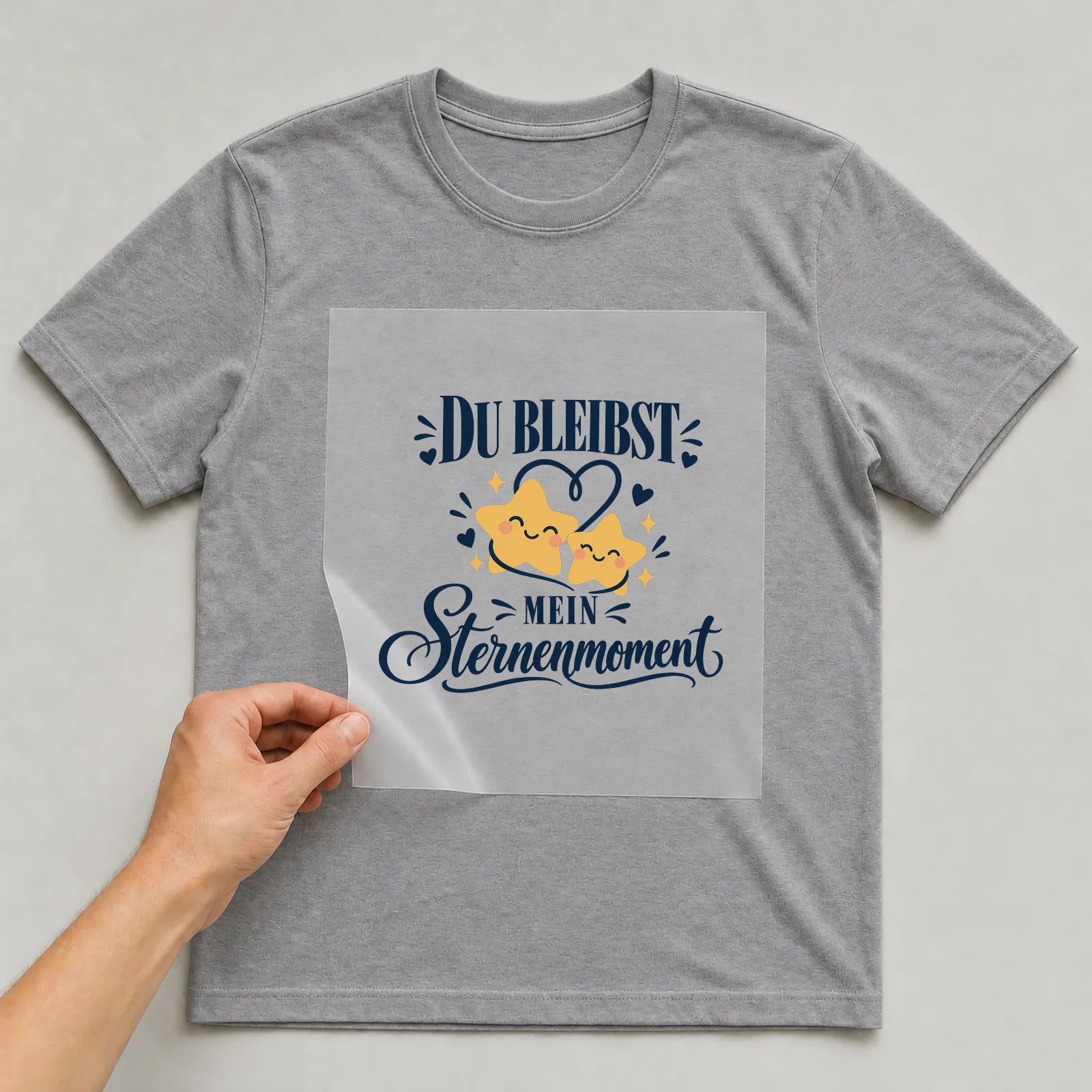 Bügelbild „Du bleibst mein Sternenmoment“ auf grauem T-Shirt, Folie wird aufgelegt