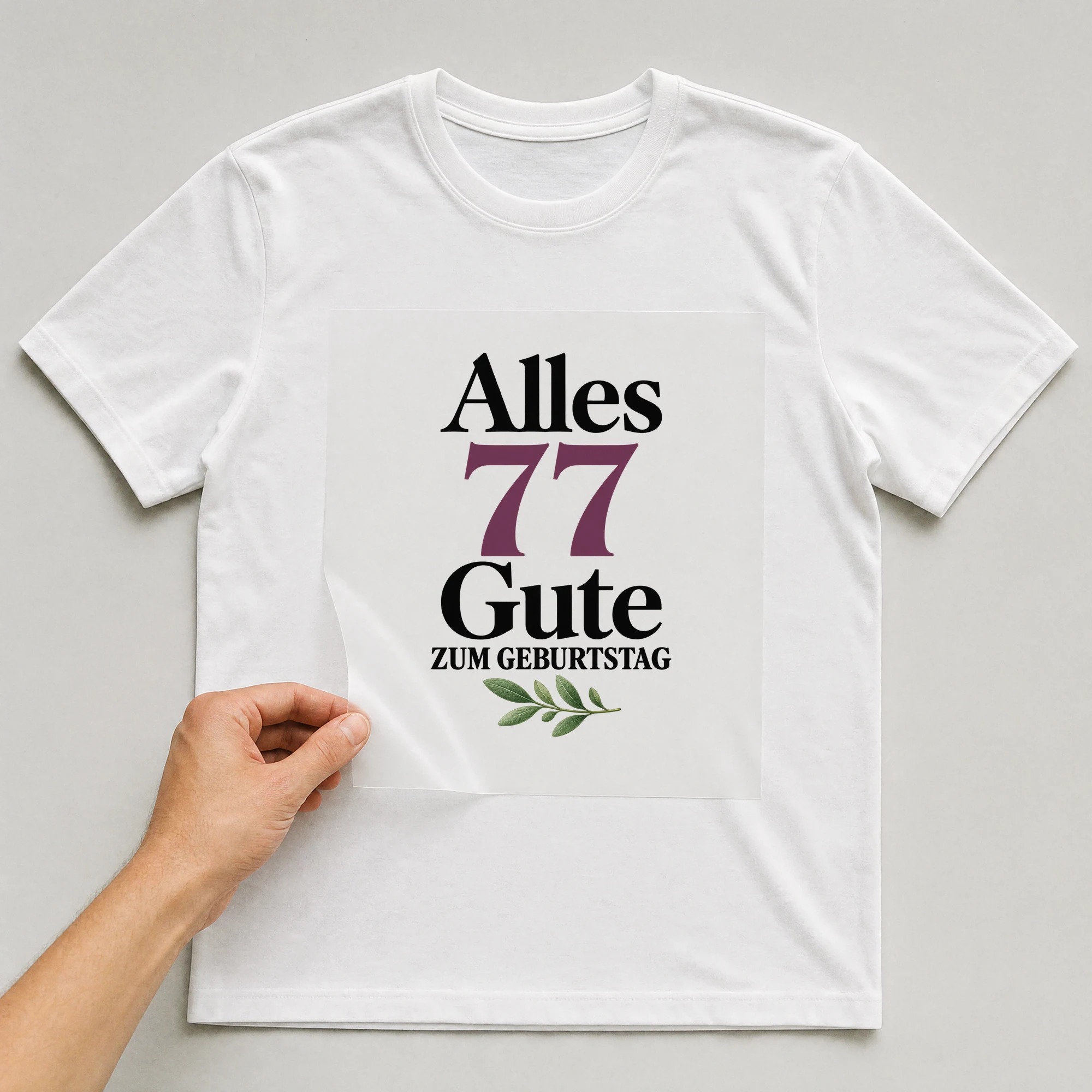 Bügelbild „Alles 77 Gute zum Geburtstag“ auf weißem T-Shirt, Folie wird aufgelegt