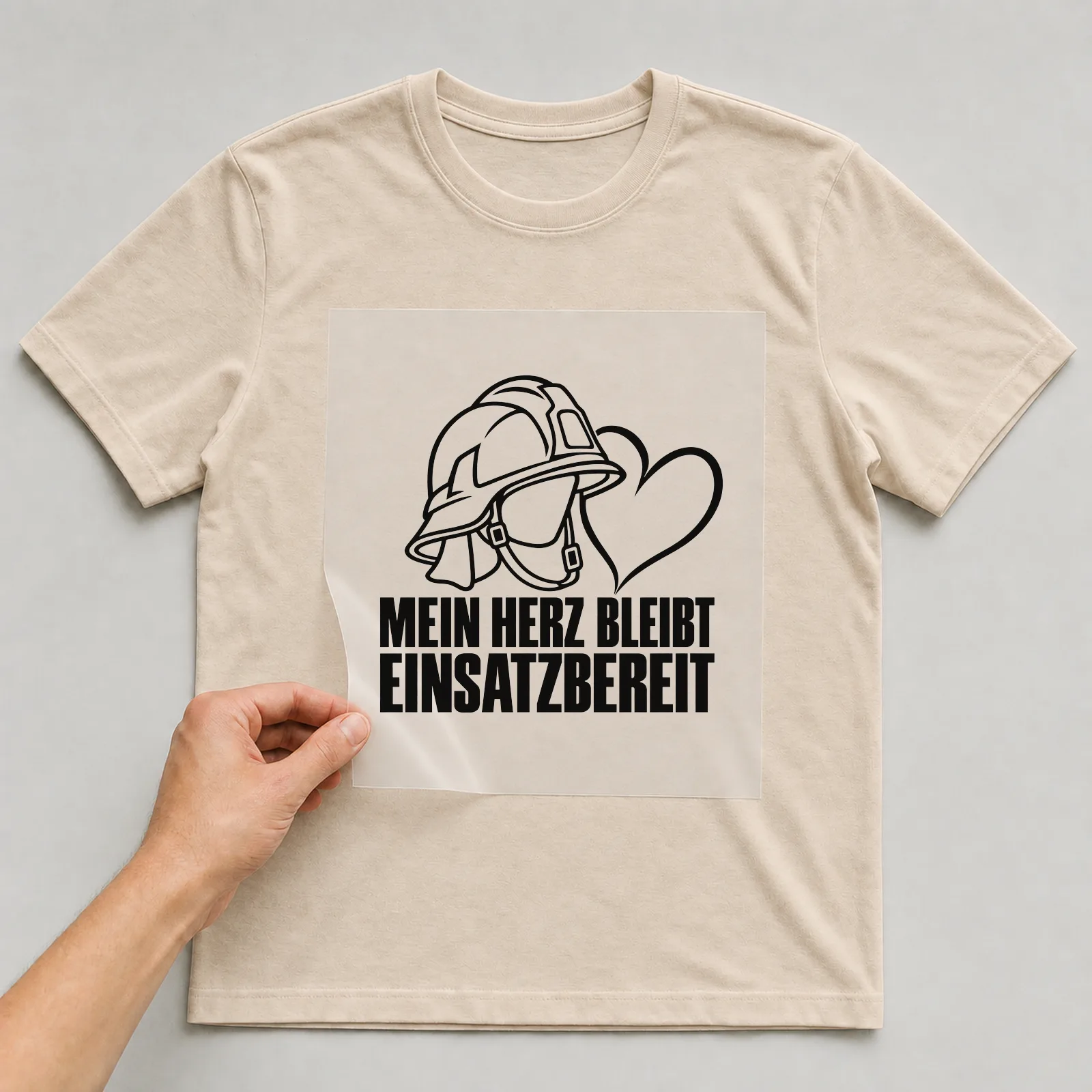 Bügelbild „Mein Herz bleibt einsatzbereit“ auf beigem T-Shirt, Folie wird aufgelegt