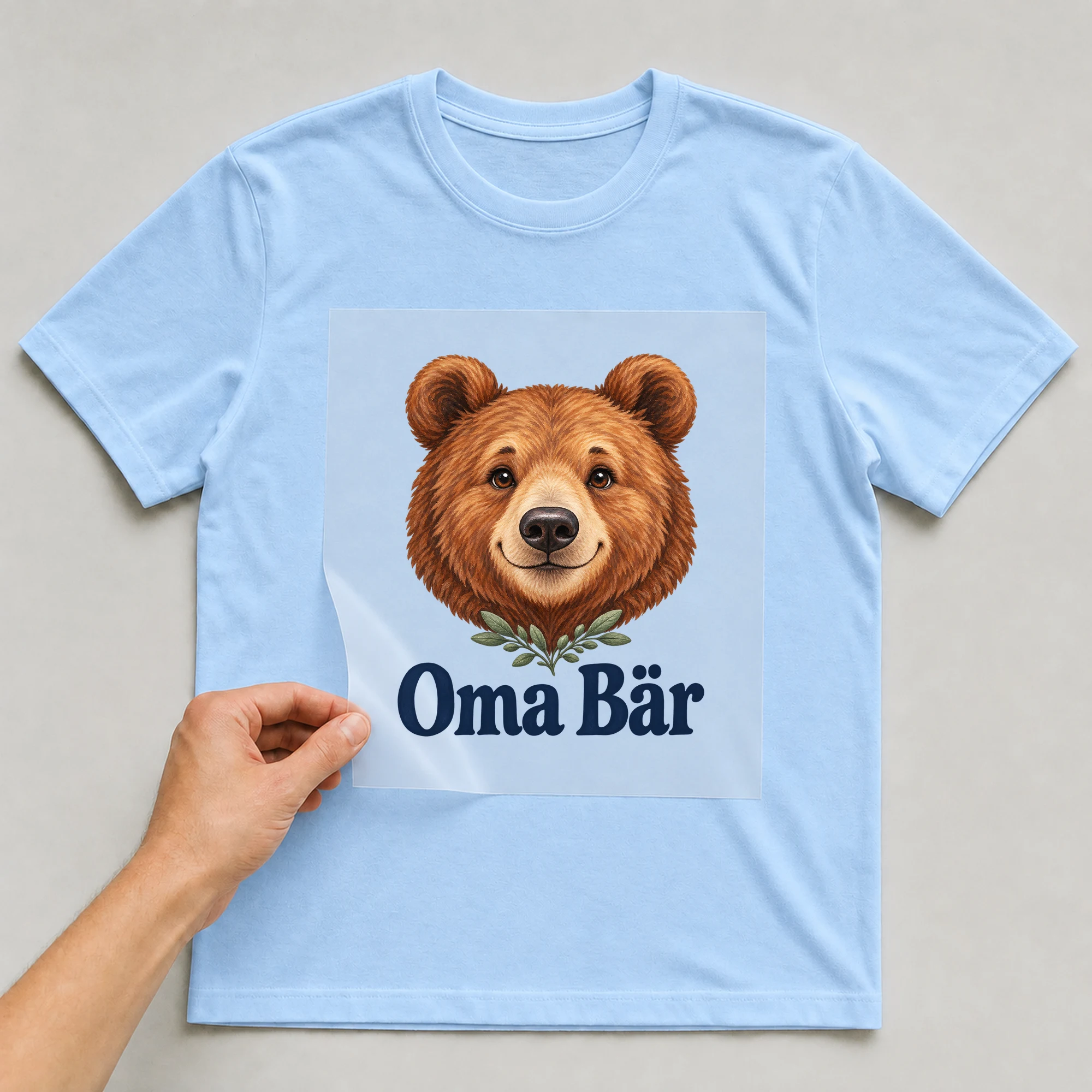 Bügelbild „Oma Bär“ auf babyblauem T-Shirt, Folie wird aufgelegt