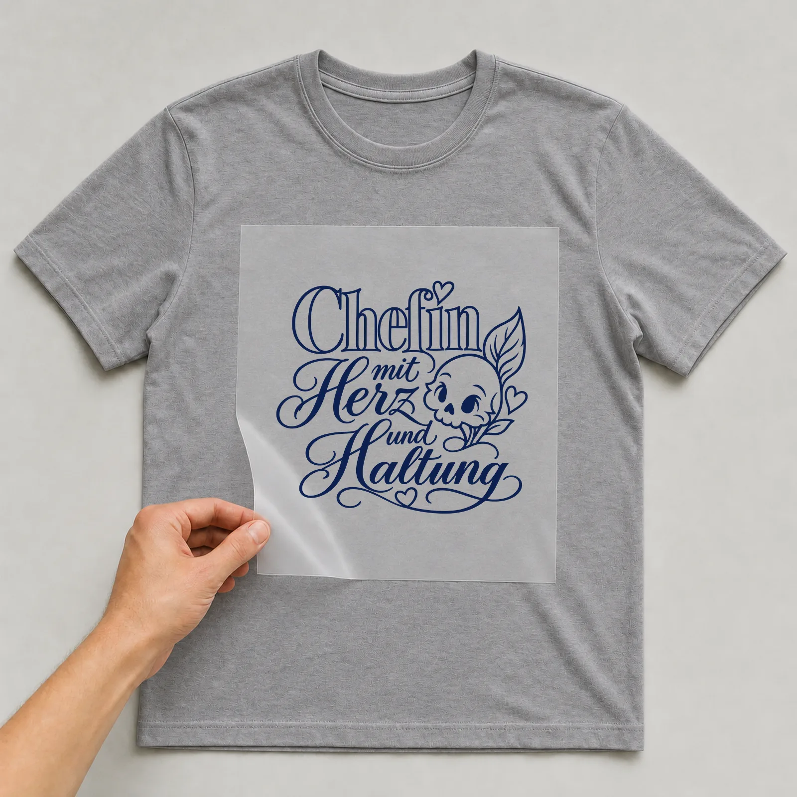 Bügelbild „Chefin mit Herz und Haltung“ auf grauem T-Shirt, Folie wird aufgelegt